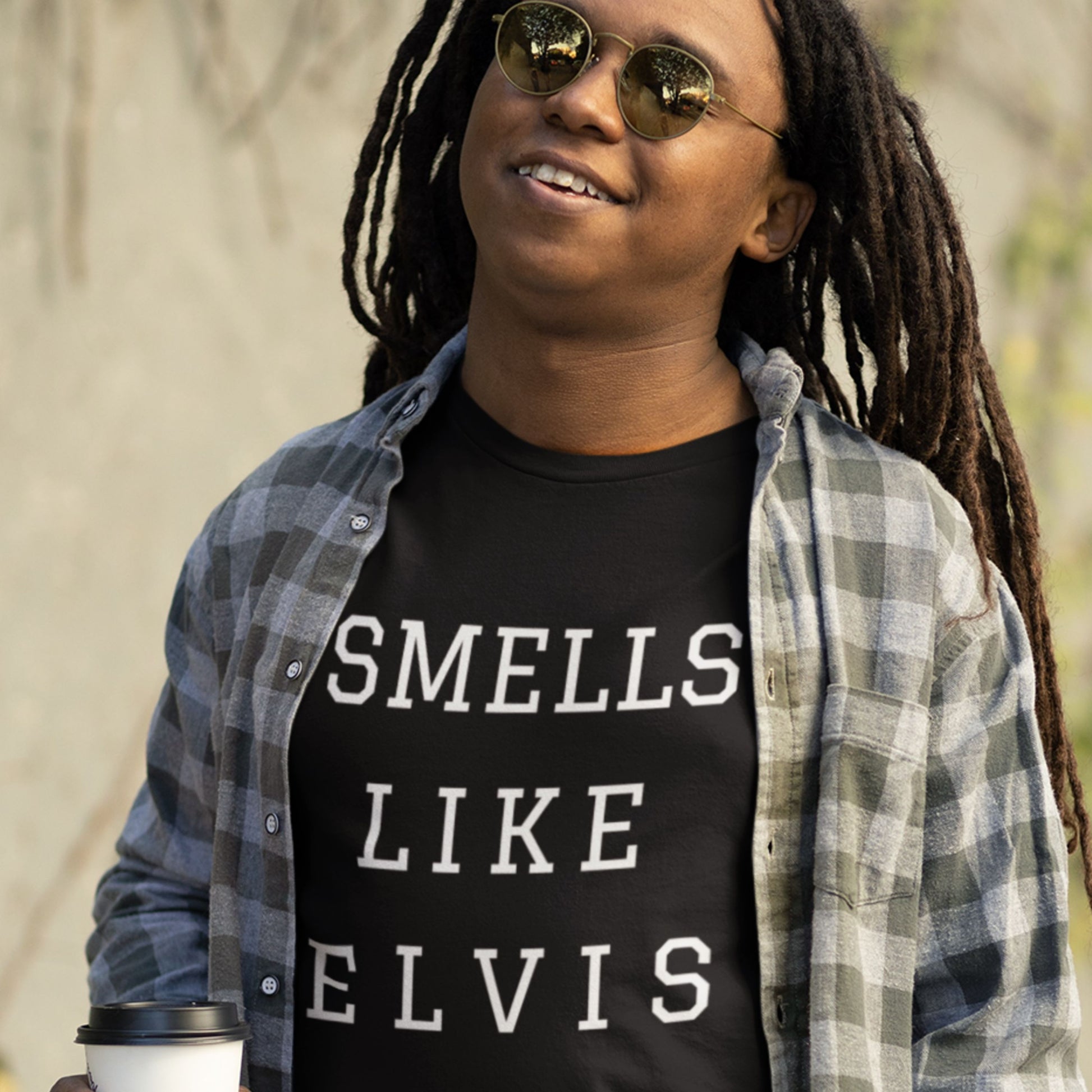 Man wearing a black t-shirt with 'smells like Elvis' text outside.