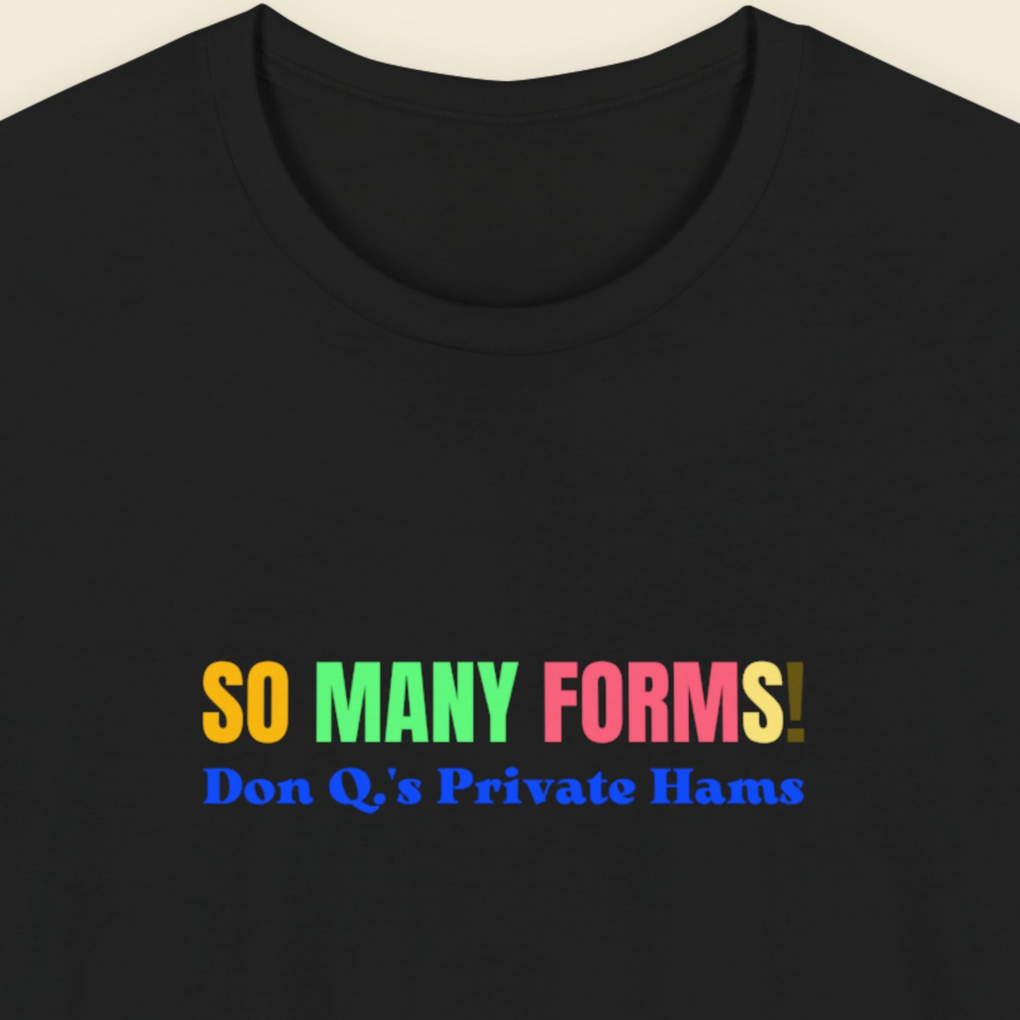 Black tee with humorous colorful text on a beige background.
