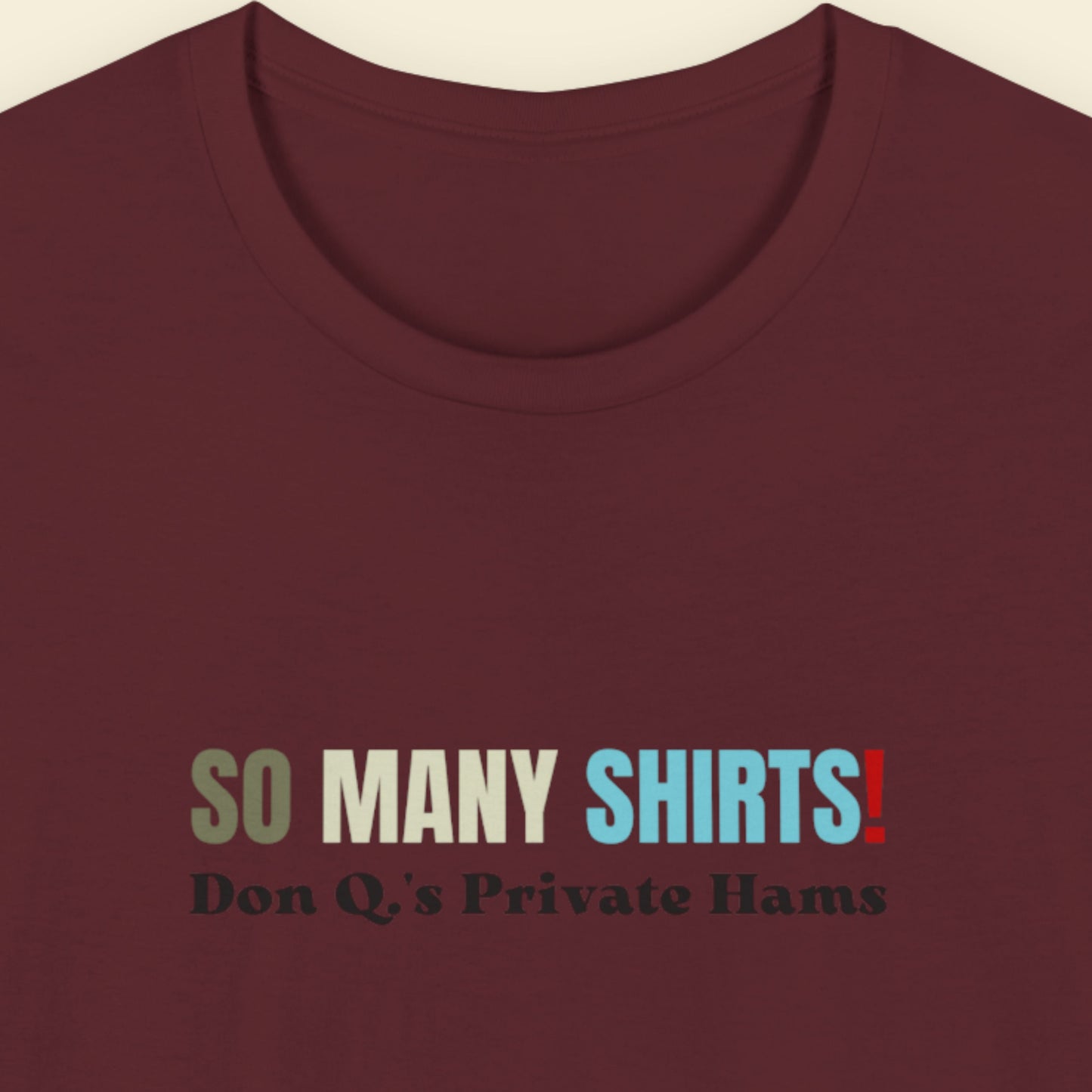 Maroon shirt with multicolored 'so many shirts!' text on a beige background.