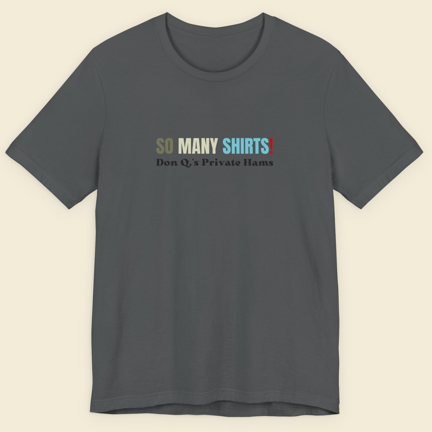 Grey shirt with multicolored 'so many shirts!' text on a beige background.