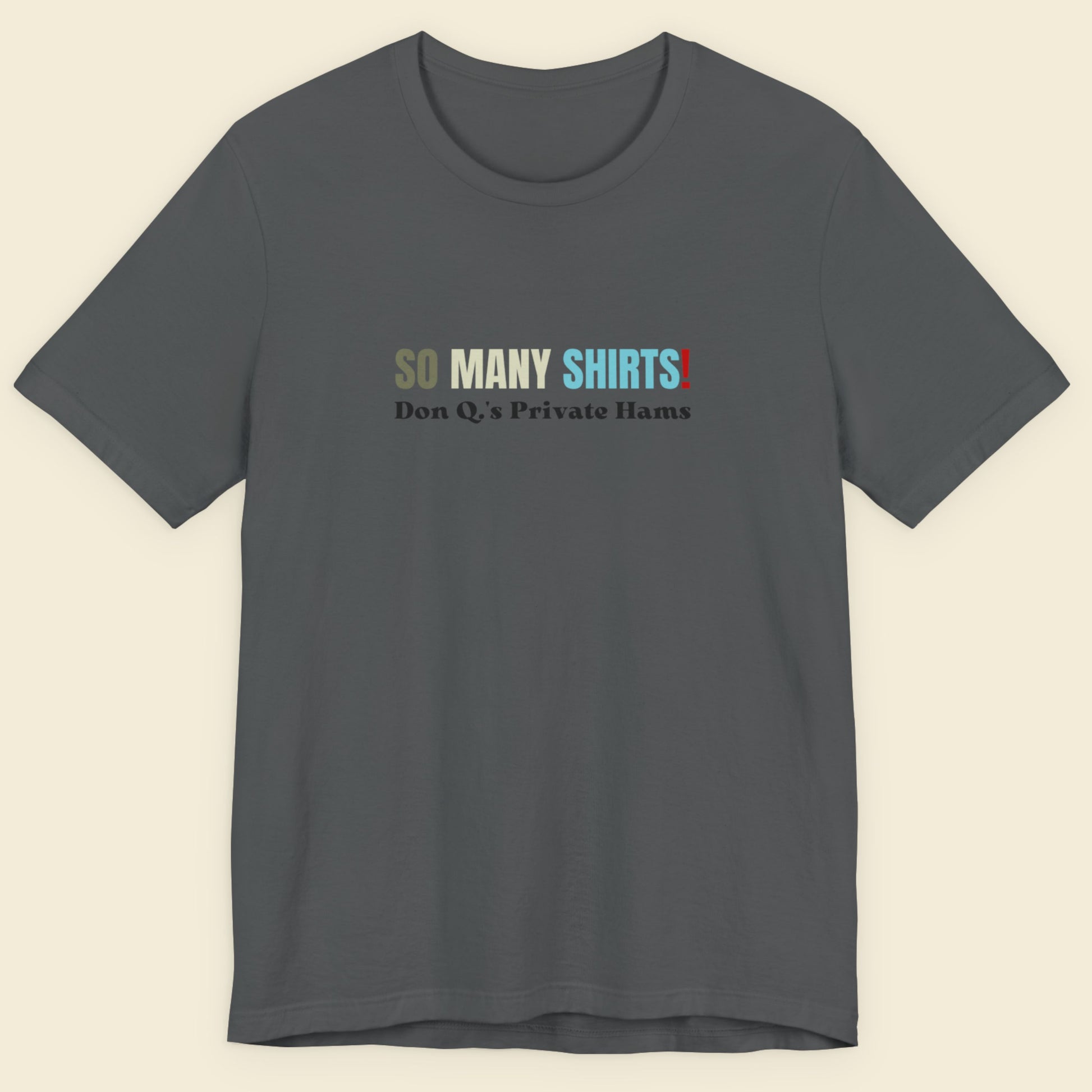 Grey shirt with multicolored 'so many shirts!' text on a beige background.