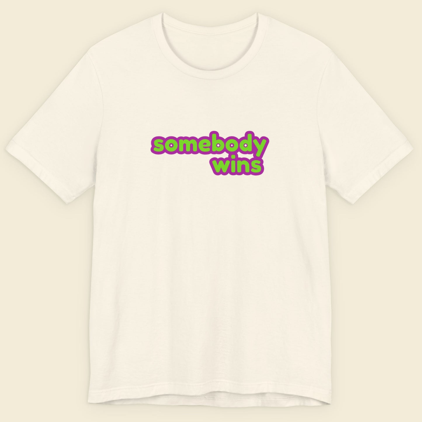 Cream colored t-shirt with multicolored 'somebody wins' text on a beige background.