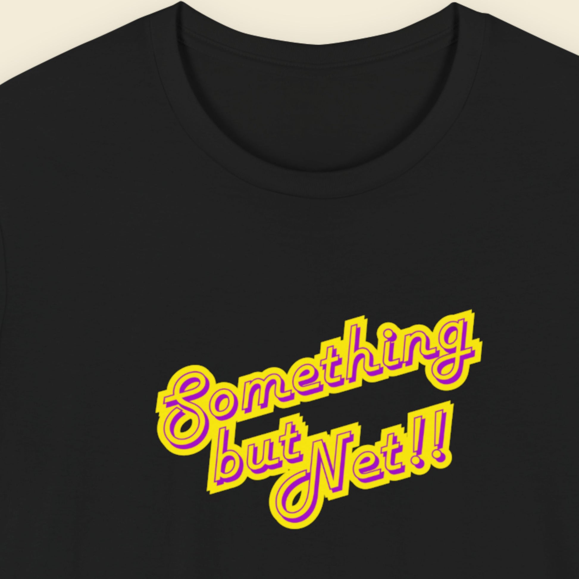 Black t-shirt with humorous colorful text on a beige background.