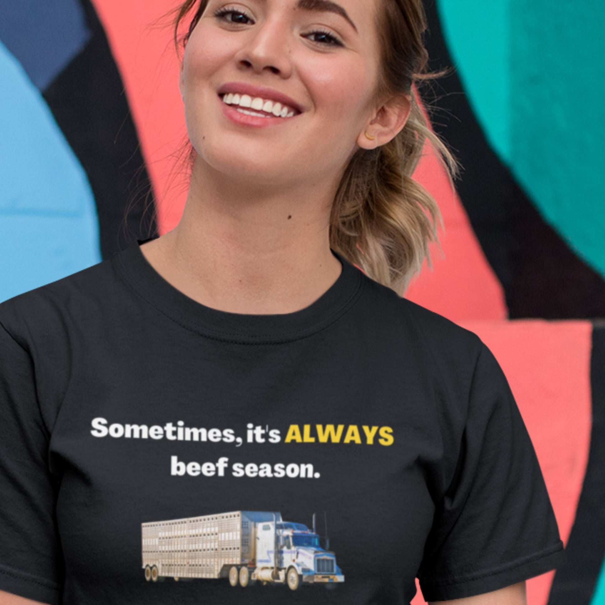 Person wearing a black t-shirt with a humorous graphic and text in front of a colorful background.