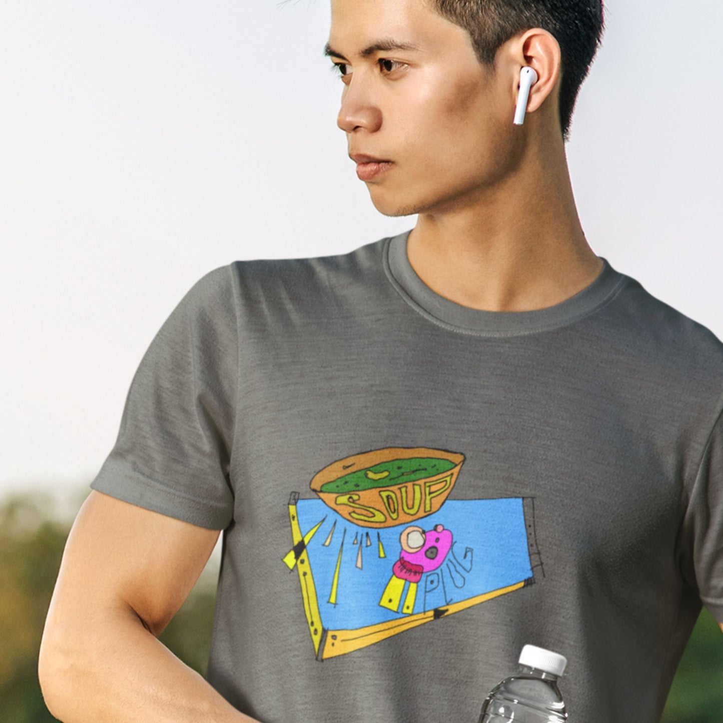 Tough guy wearing first generation earpods and wearing an army green t-shirt with a colorful abstract drawing on a beach probably.