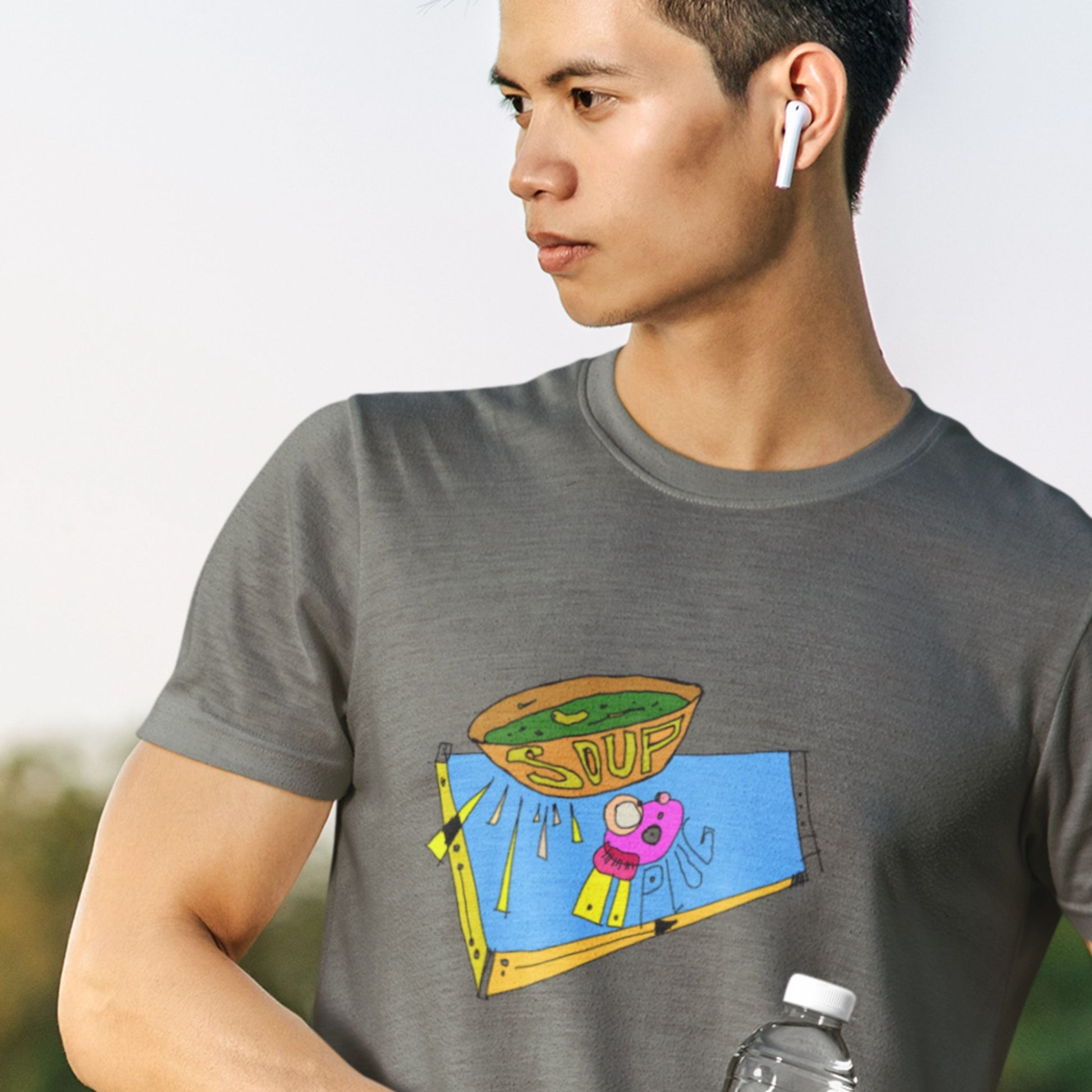 Tough guy wearing first generation earpods and wearing an army green t-shirt with a colorful abstract drawing on a beach probably.
