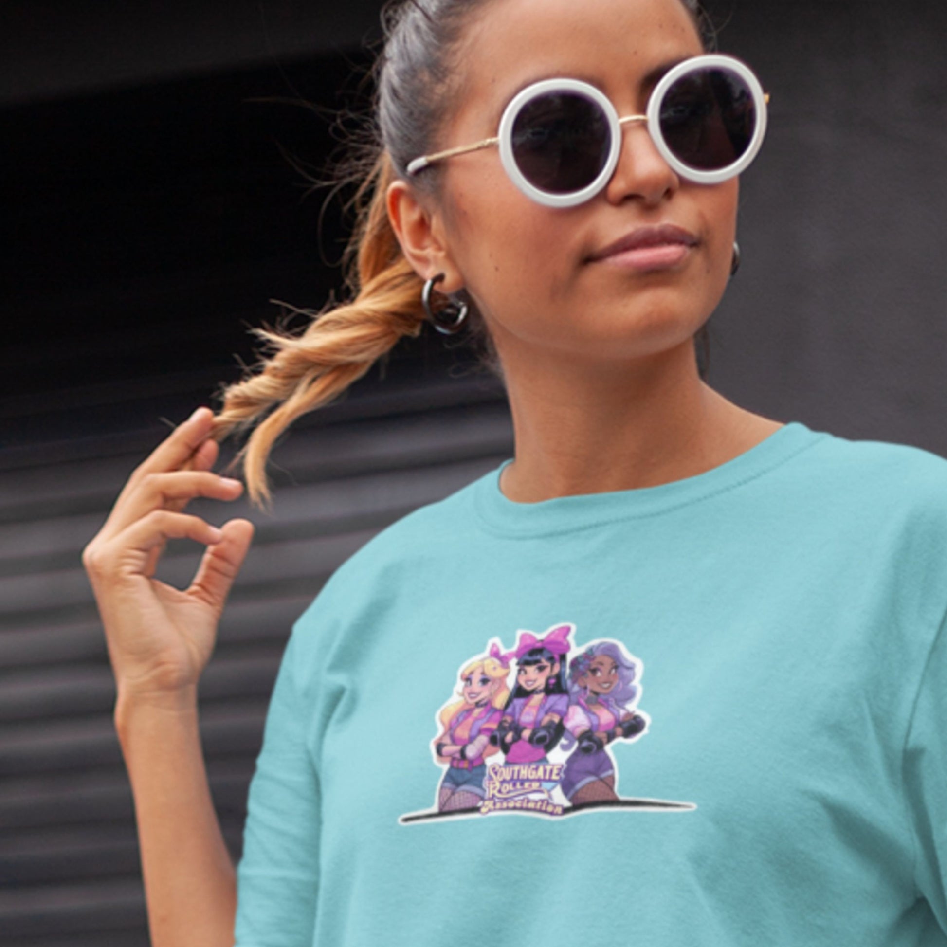 Model wearing a tuquoise shirt with a die cut sticker style graphic of famous power pop group, Southgate Roller Association