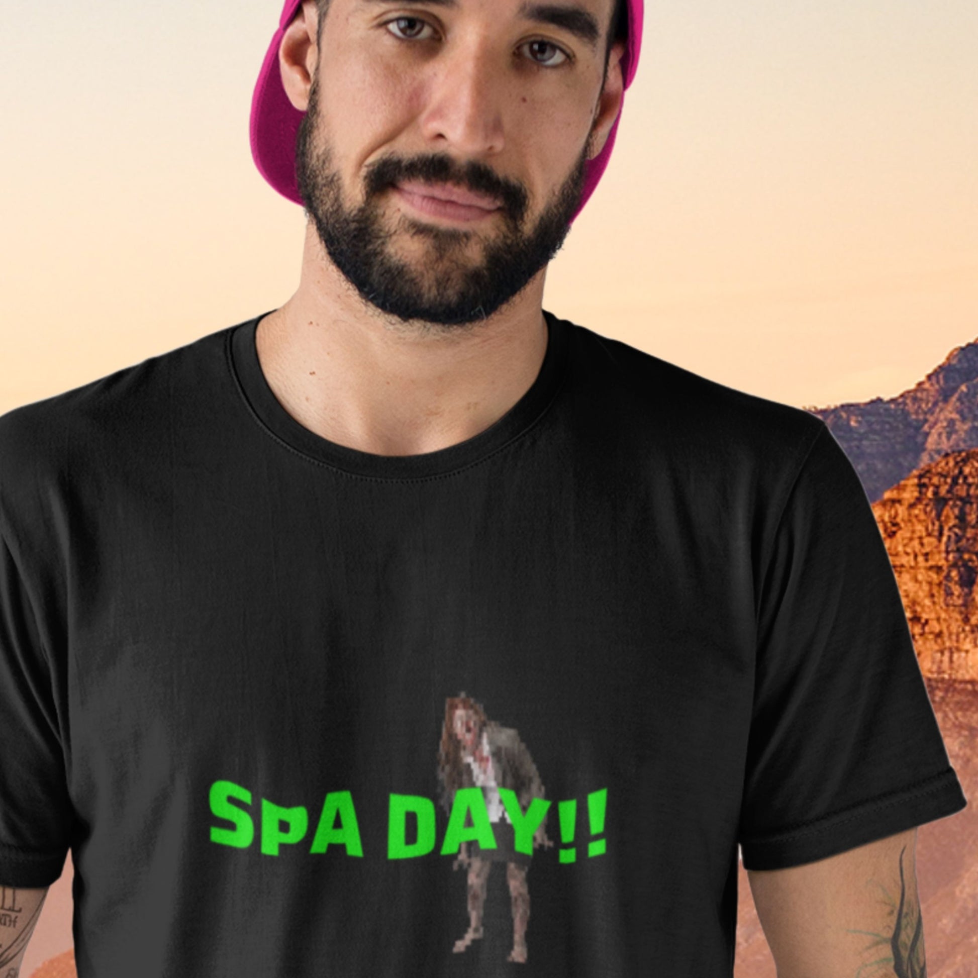Man wearing a black t-shirt with 'SPA DAY!!' text and graphic, standing against a desert landscape.