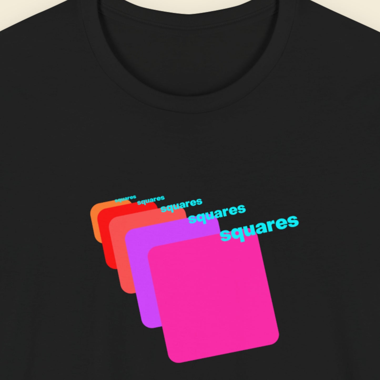 Black t-shirt with colorful 'squares' graphic design on a beige background.