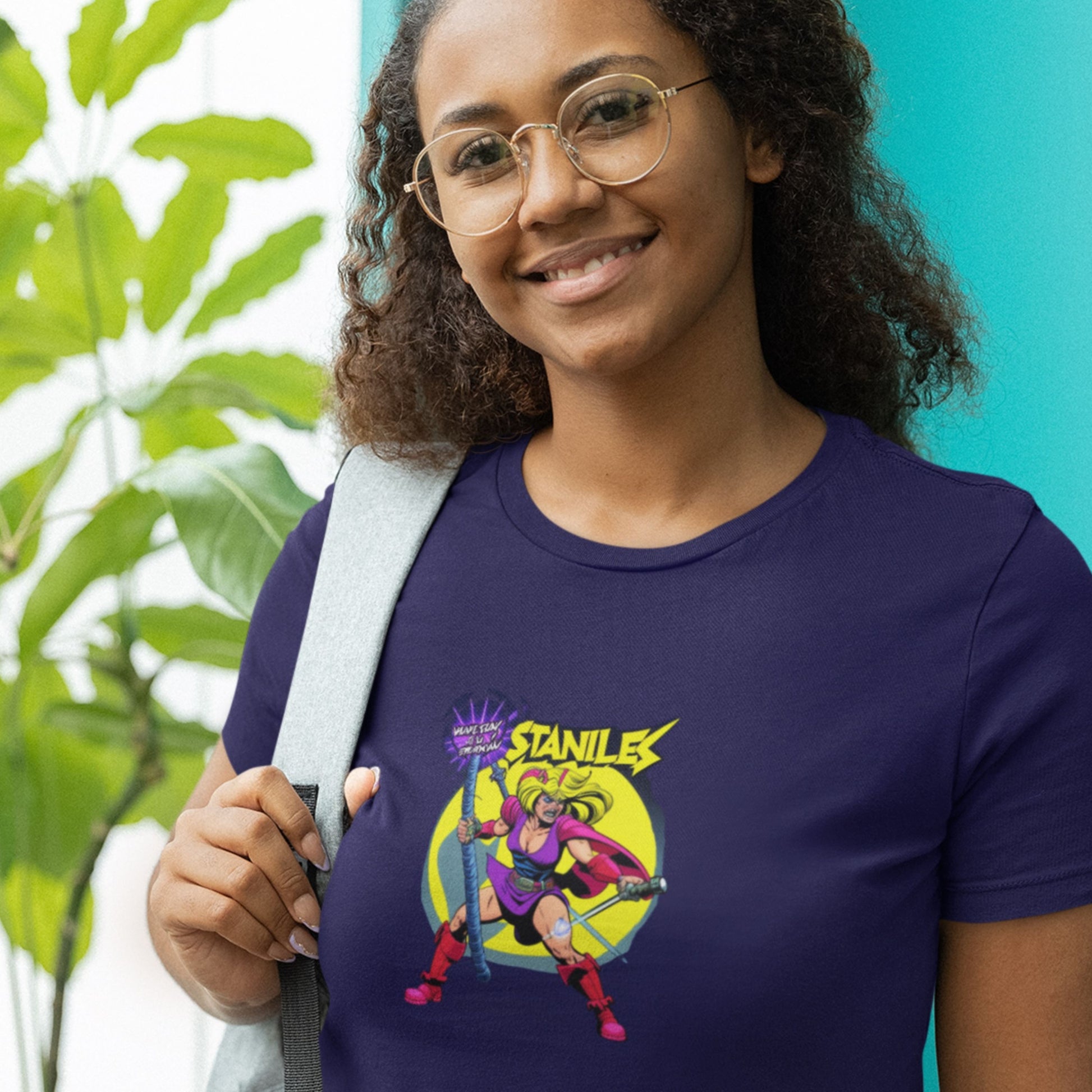 Smiling woman wearing a navy blue t-shirt with a fun, 80's inspired colorful cartoon illustration in a plant store.