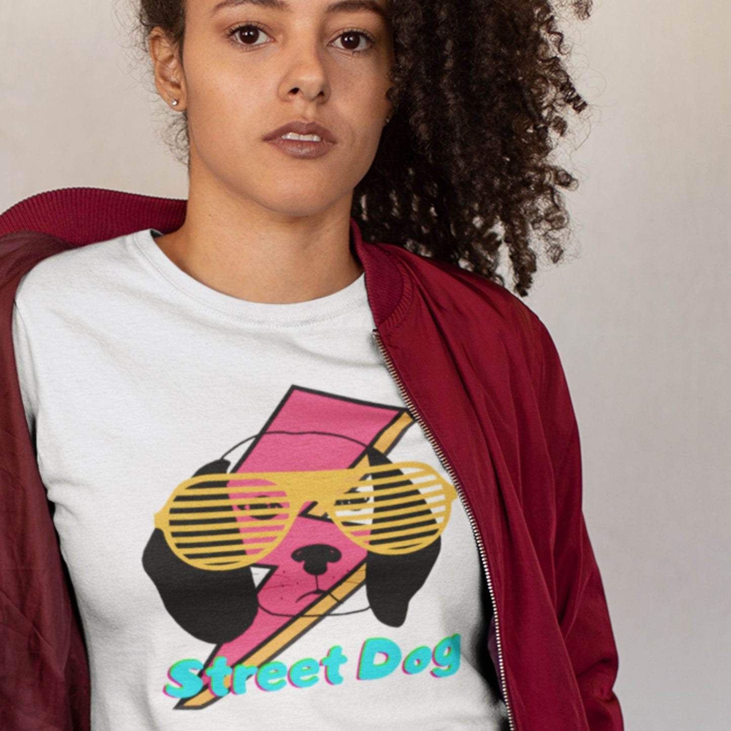 Person wearing a white t-shirt with a colorful dog graphic and 'Street Dog' text, paired with a red jacket.