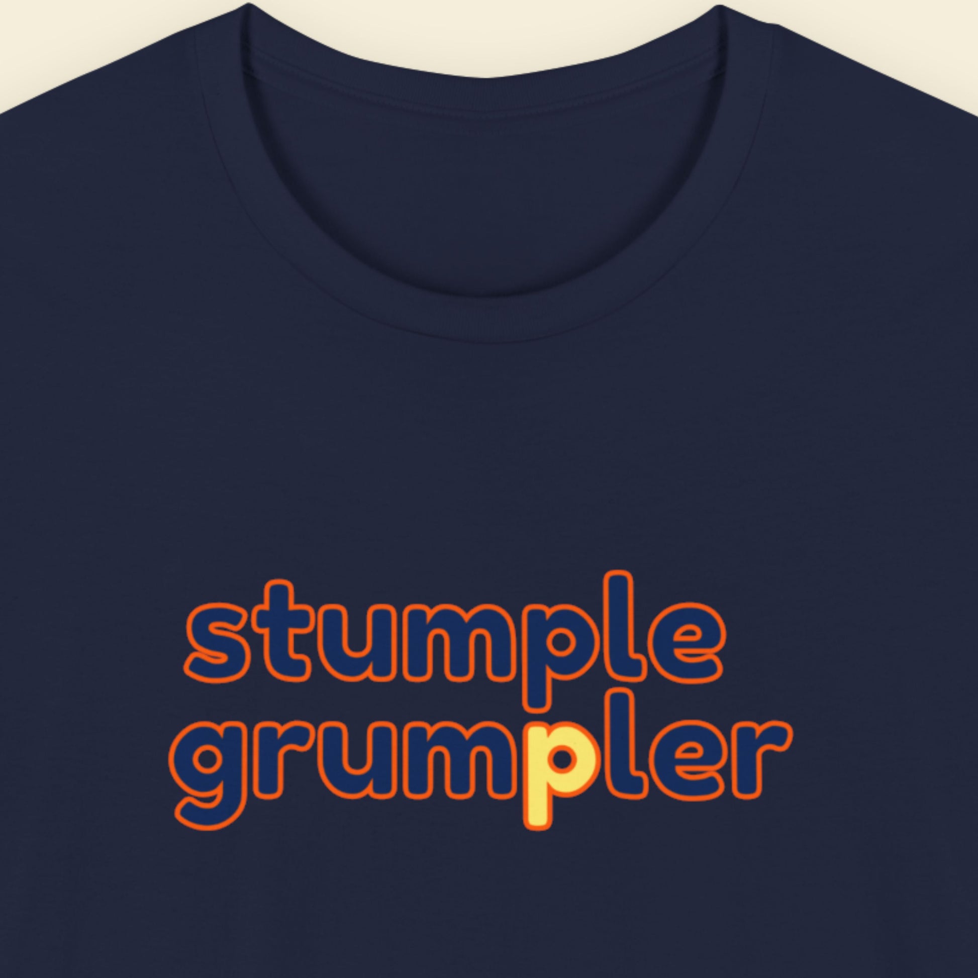Navy blue t-shirt with multicolored 'stumple grumpler' text on a beige background.