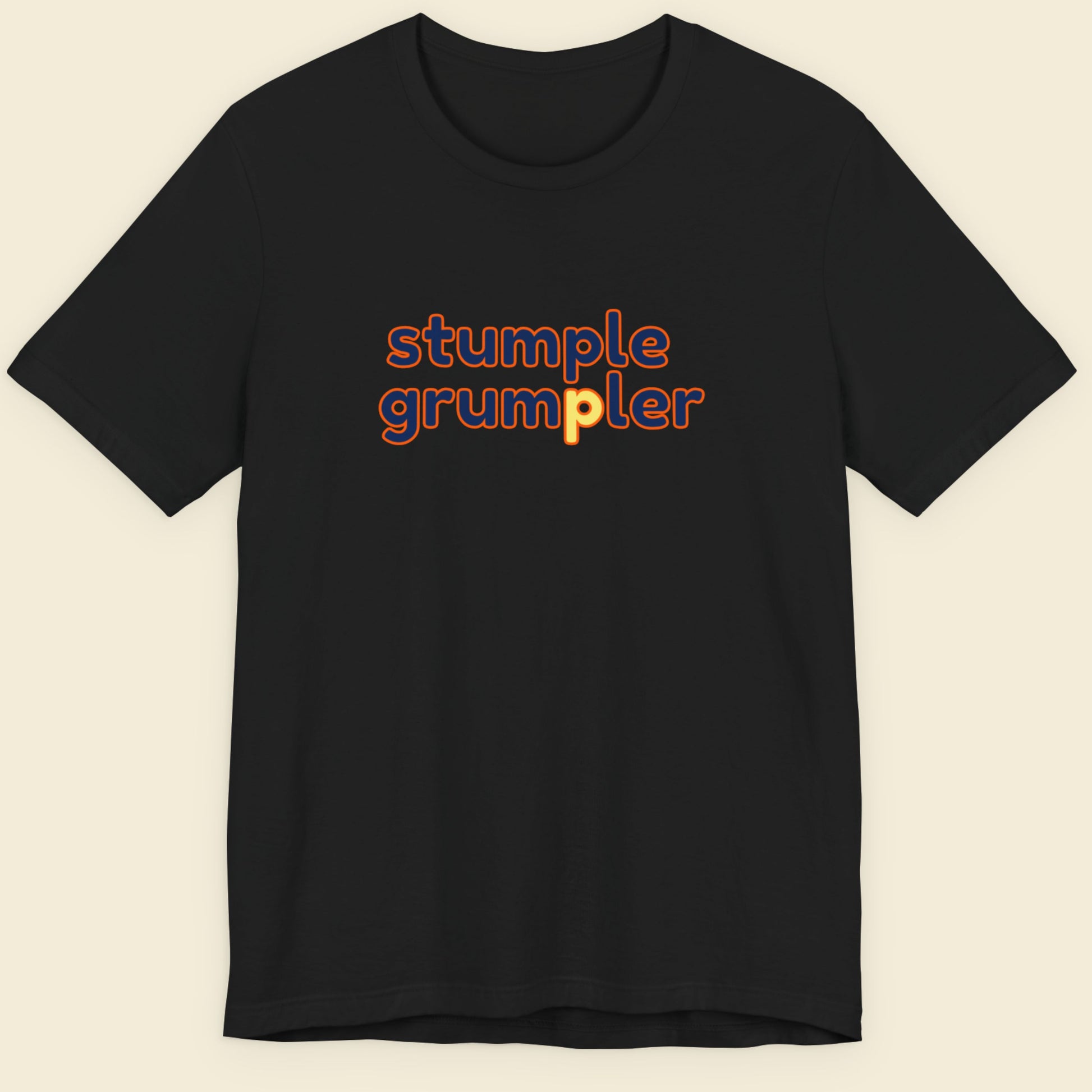 Black t-shirt with multicolored 'stumple grumpler' text on a beige background.