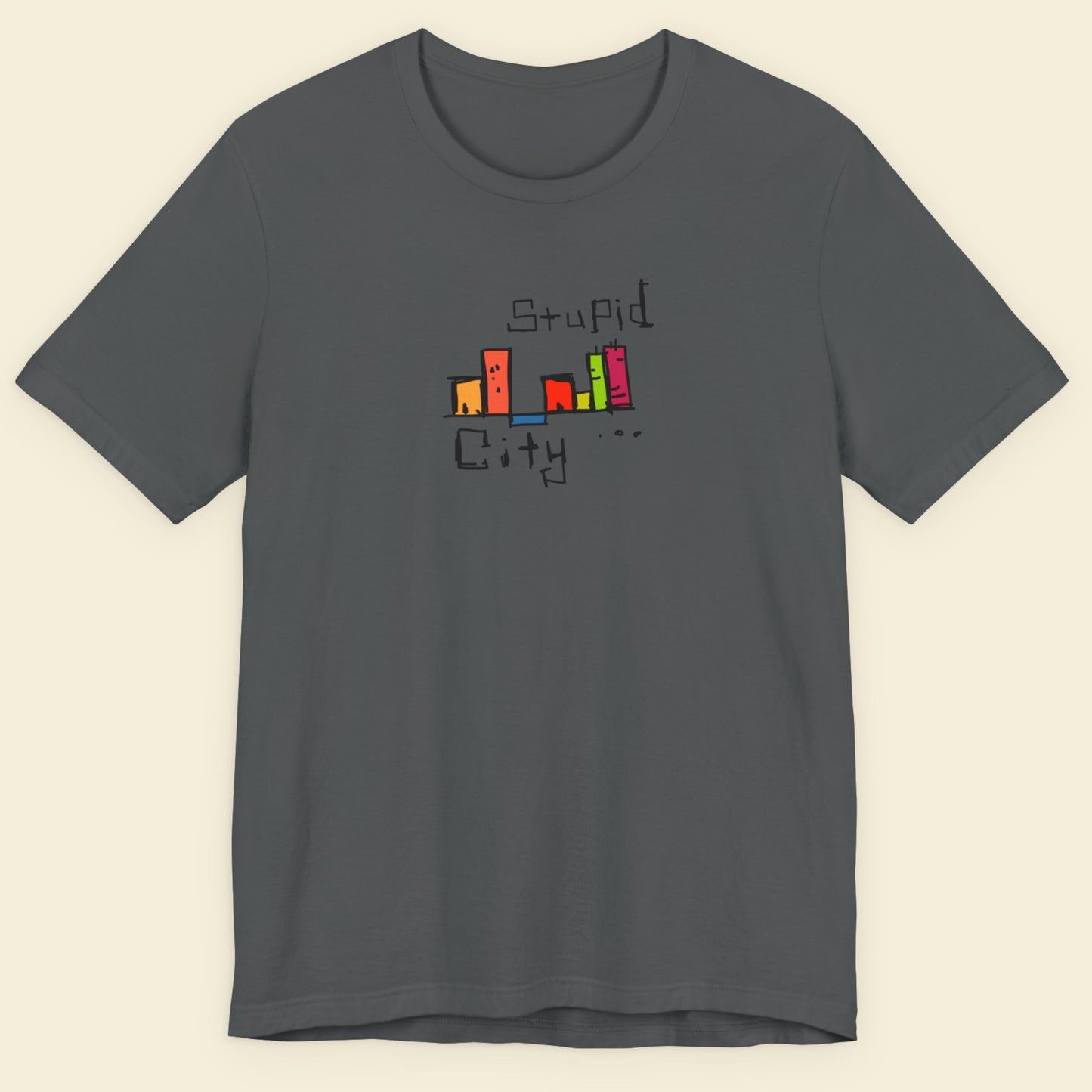 Gray t-shirt with colorful 'Stupid City' graphic design on a beige background.
