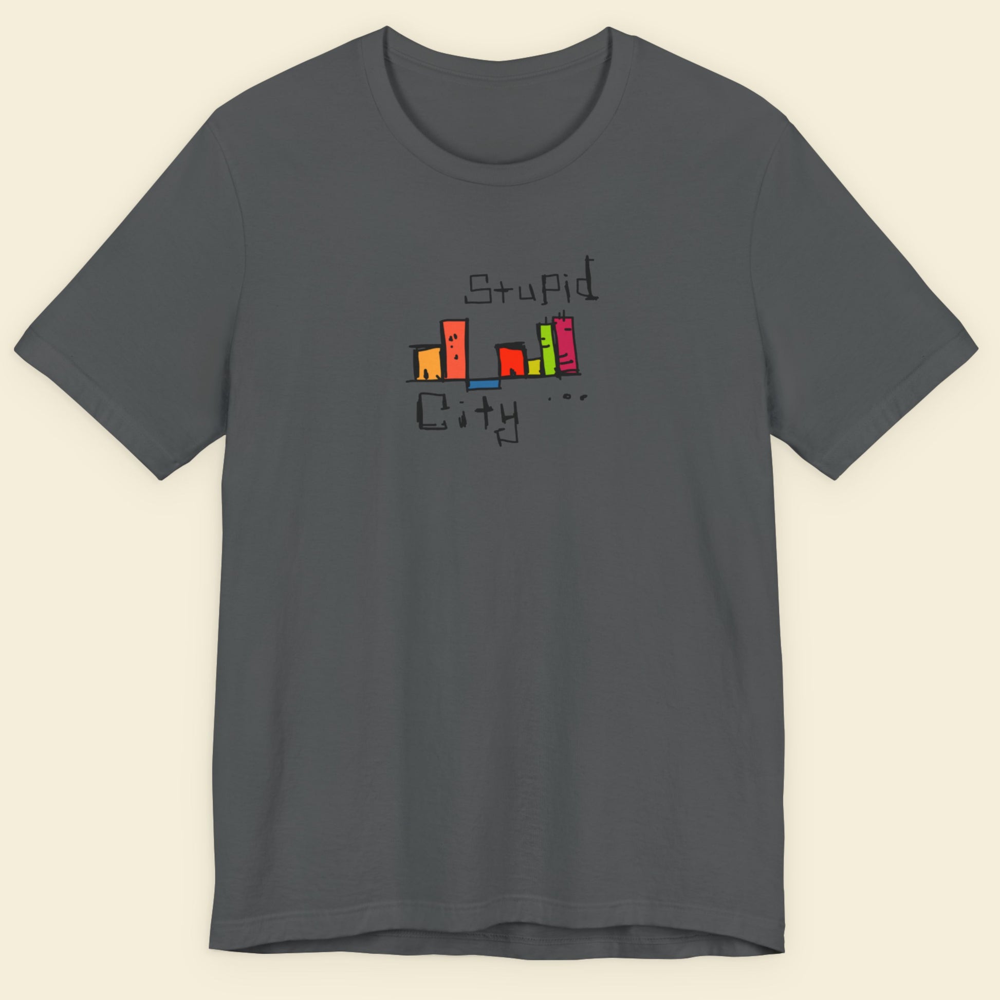 Gray t-shirt with colorful 'Stupid City' graphic design on a beige background.