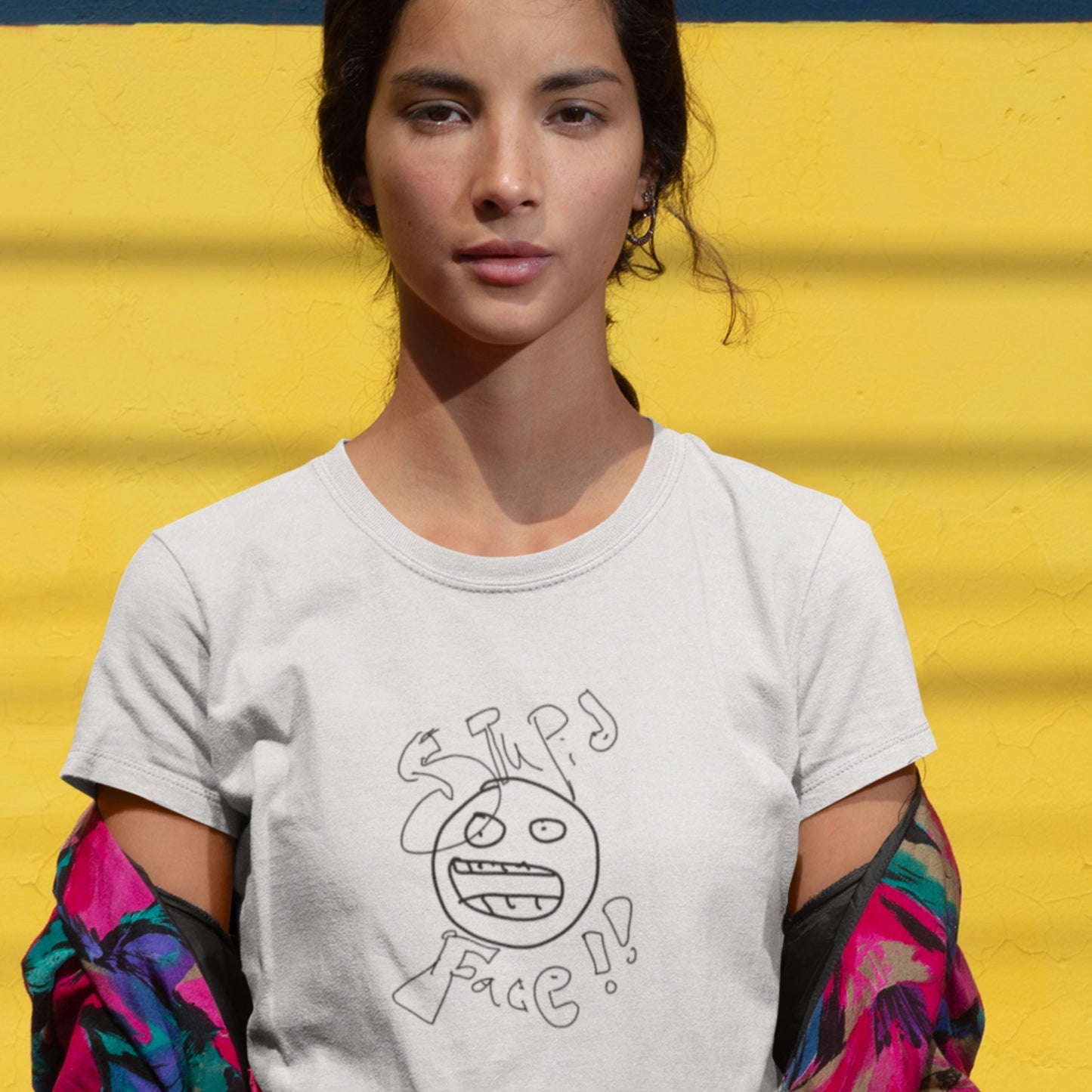 woman wearing a white t-shirt with a line drawing and the words 'stupid face' written on it