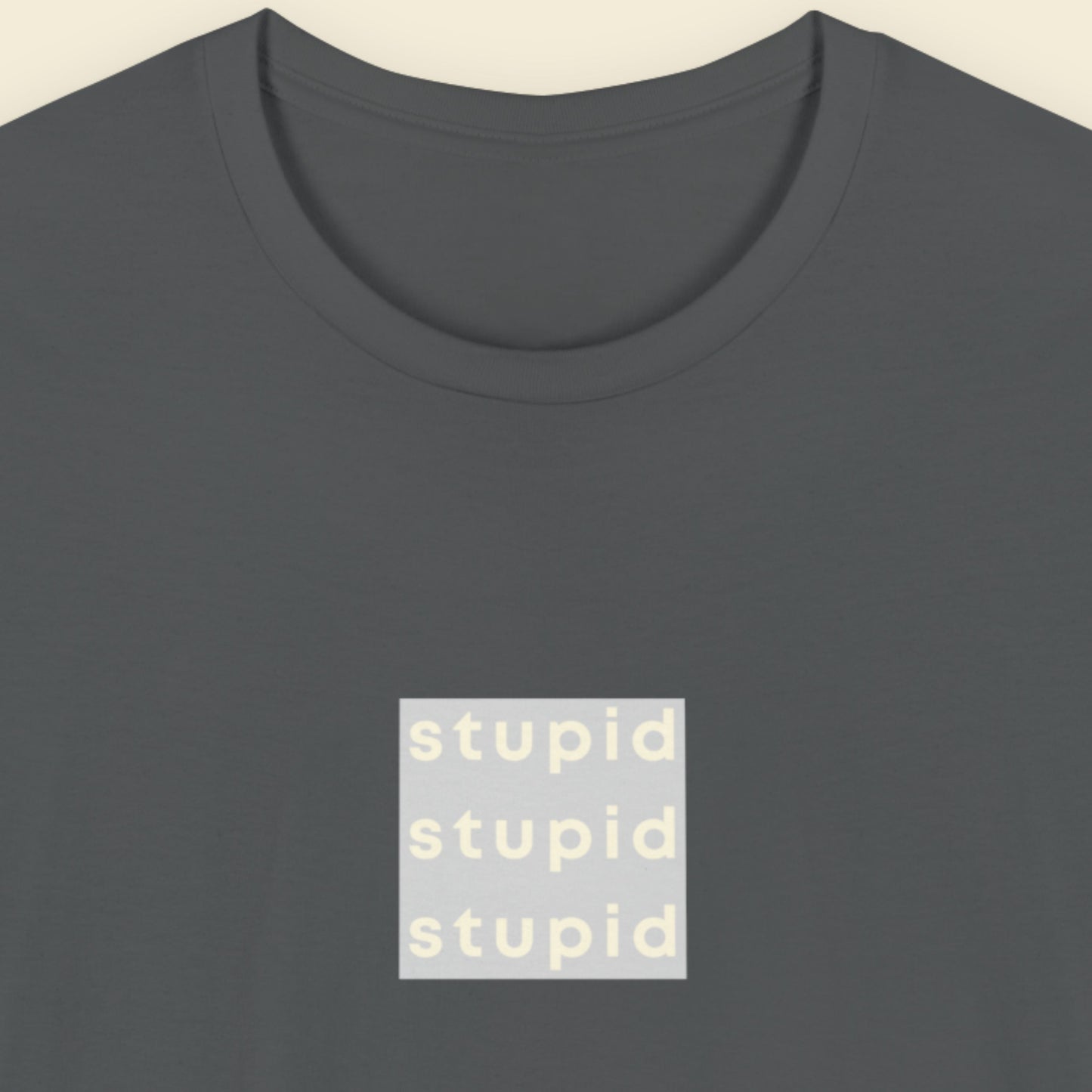 Dark grey t-shirt with humorous colorful text on a beige background.
