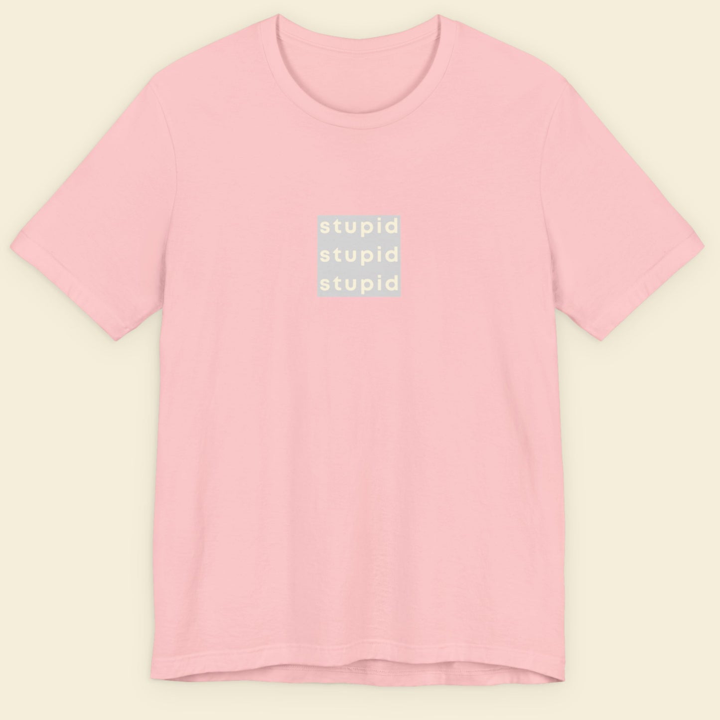 Pink t-shirt with 'stupid' text on a beige background.