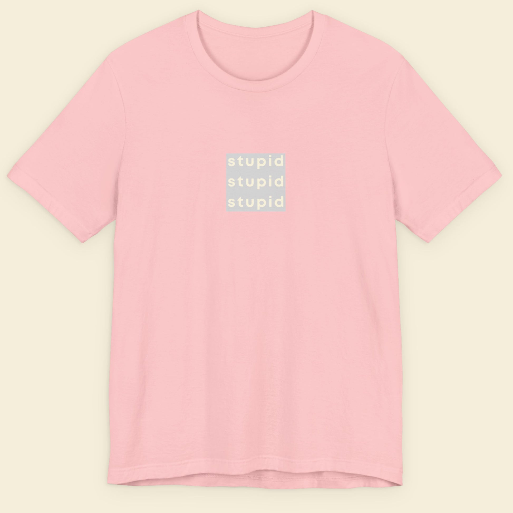 Pink t-shirt with 'stupid' text on a beige background.