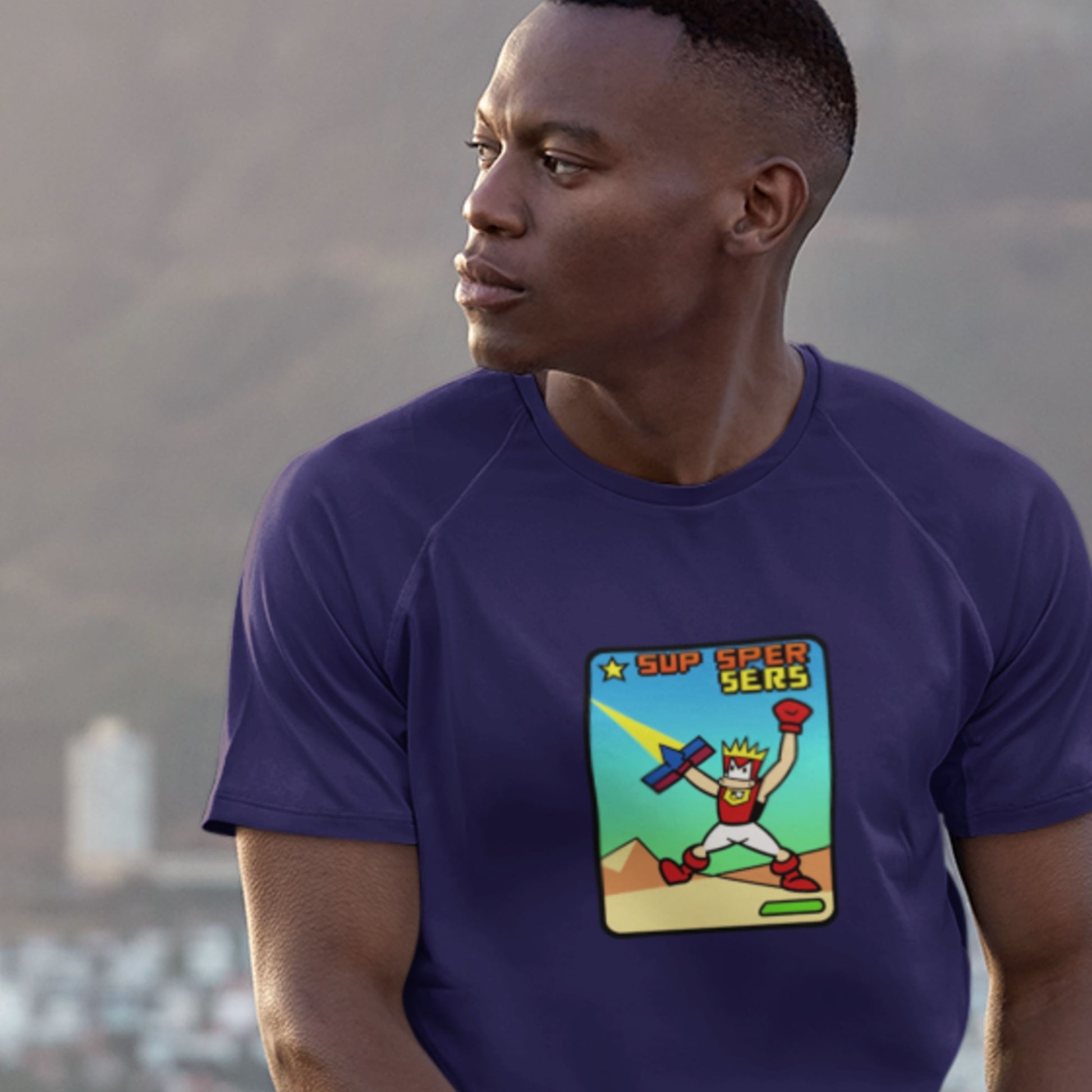 Man wearing a navy t-shirt with a fun, colorful cartoon illustration outside.