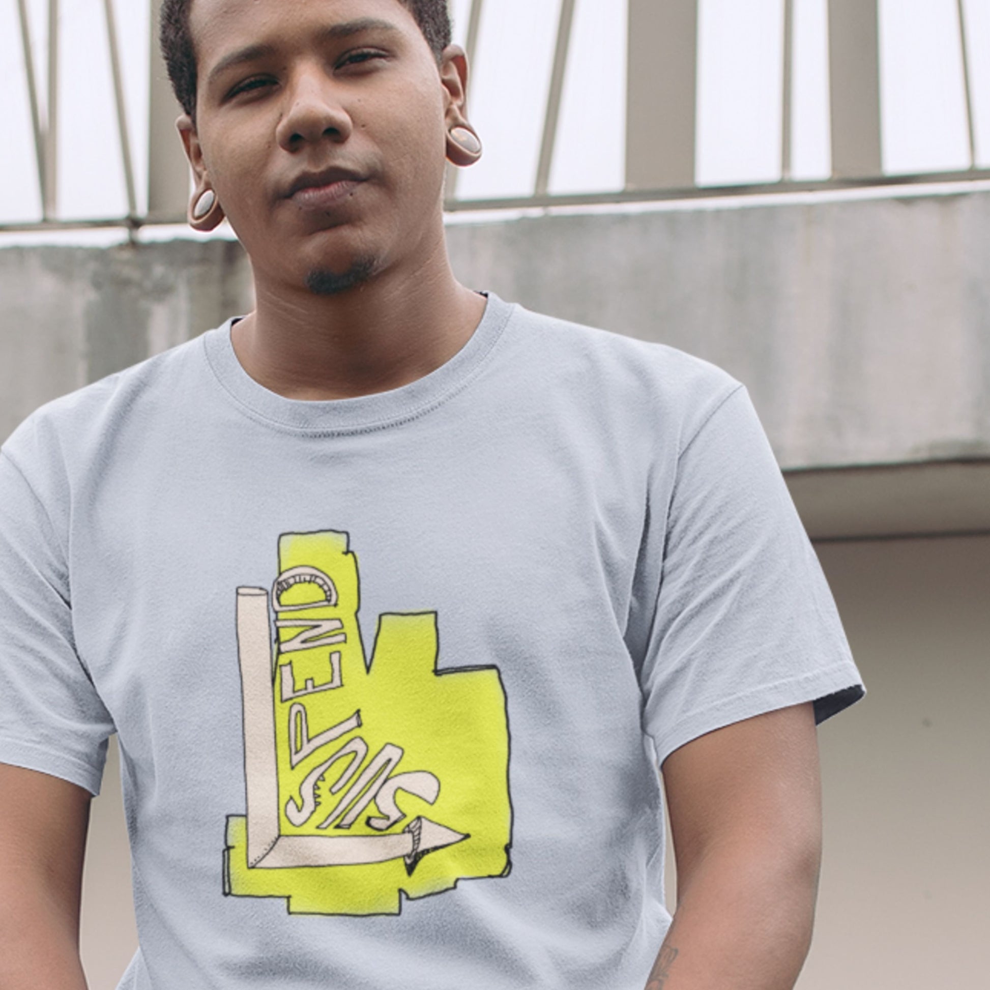 Man wearing a light blue t-shirt with a colorful abstract drawing outdoors.