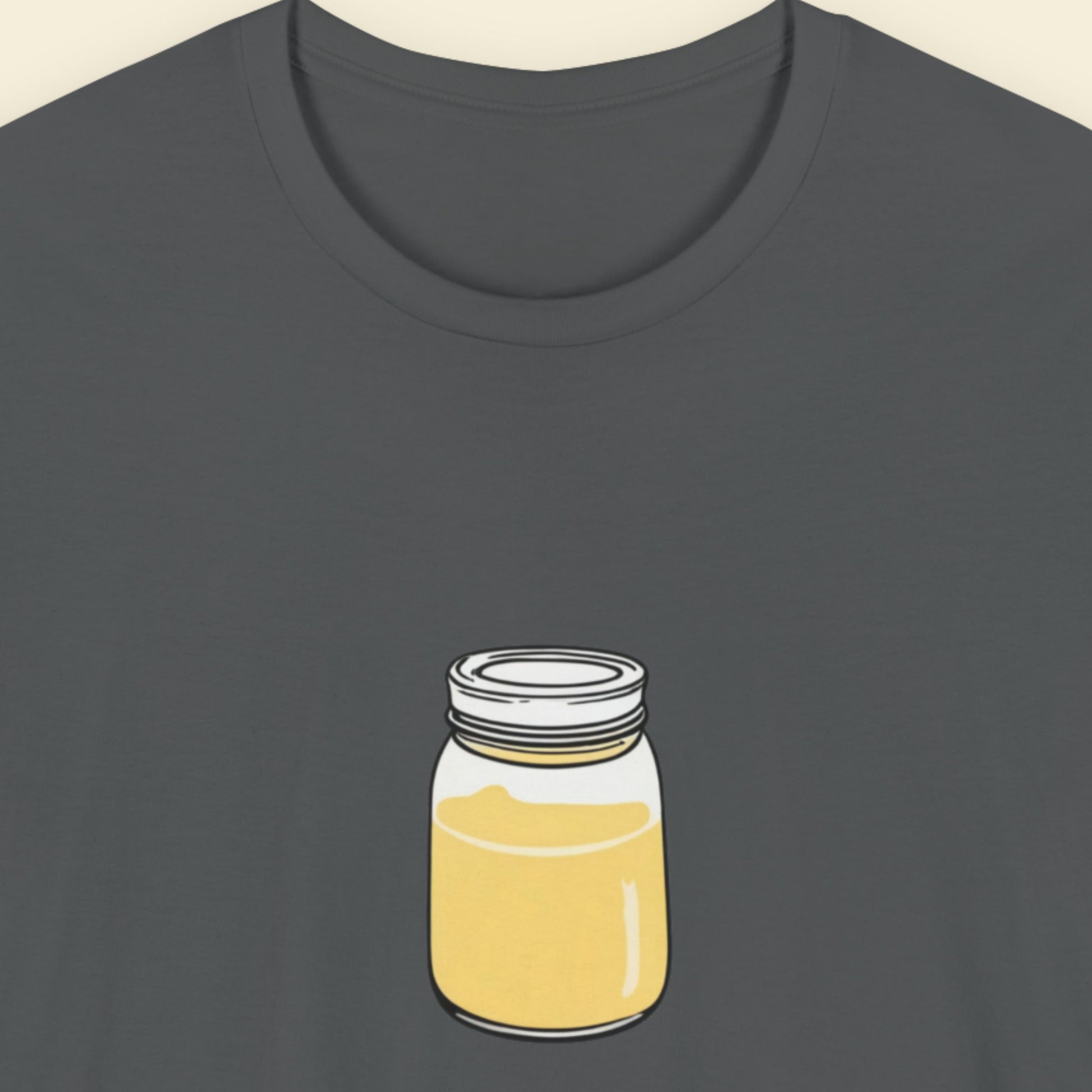 Grey shirt with a drawing of a jar of swirling yellow liquid on a beige background.