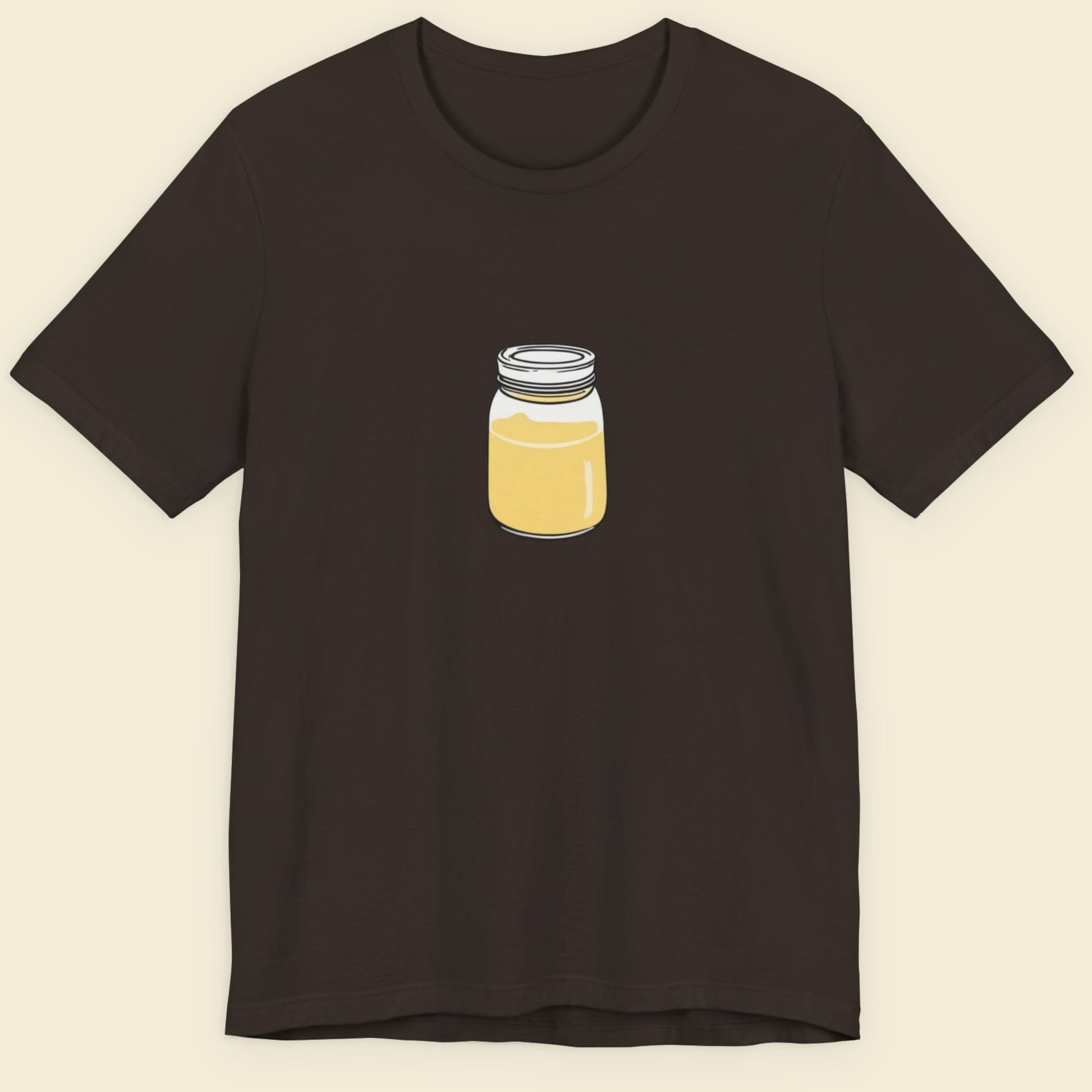 Brown shirt with a drawing of a jar of swirling yellow liquid on a beige background.