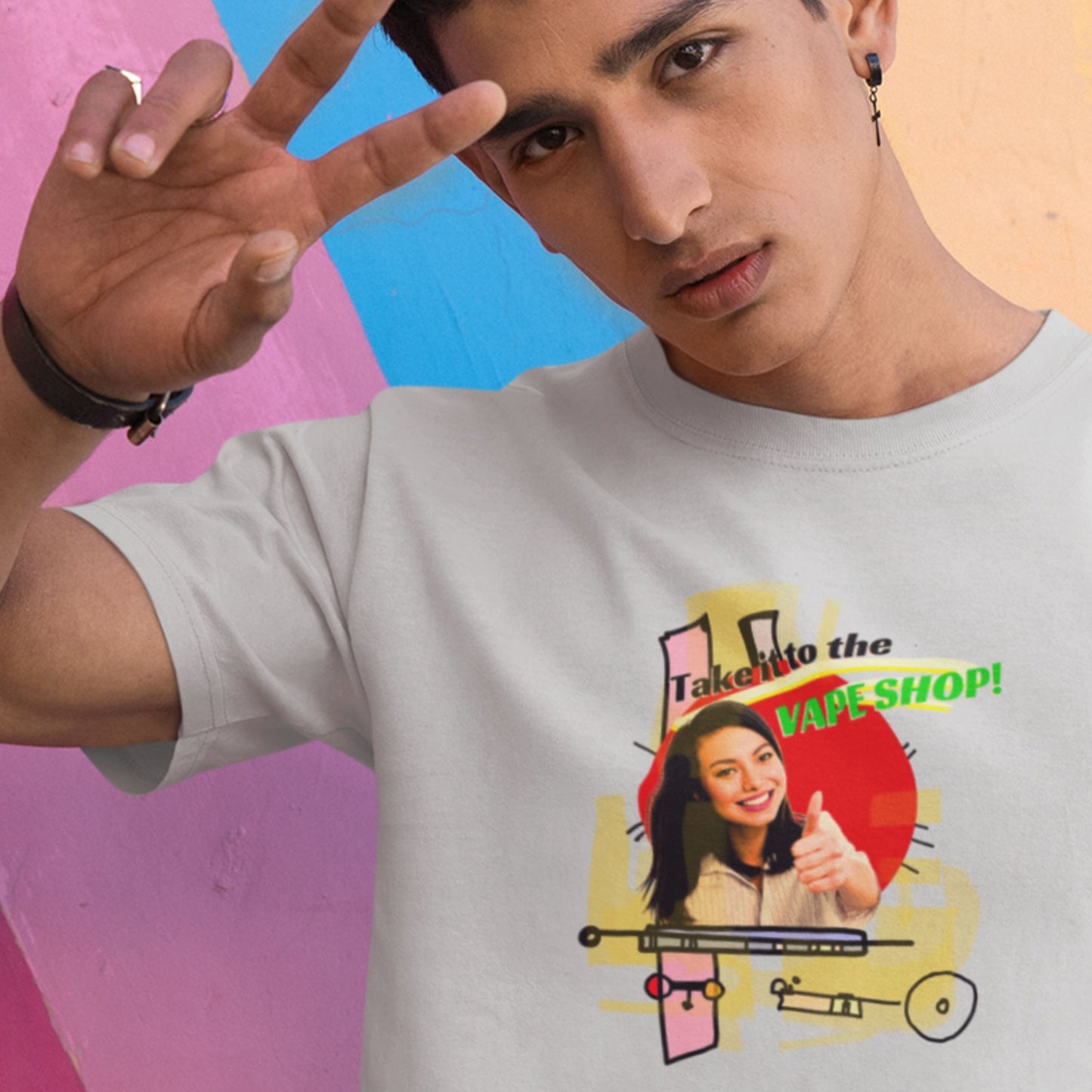 Person wearing a t-shirt with a graphic design and text, making a peace sign against a colorful background.