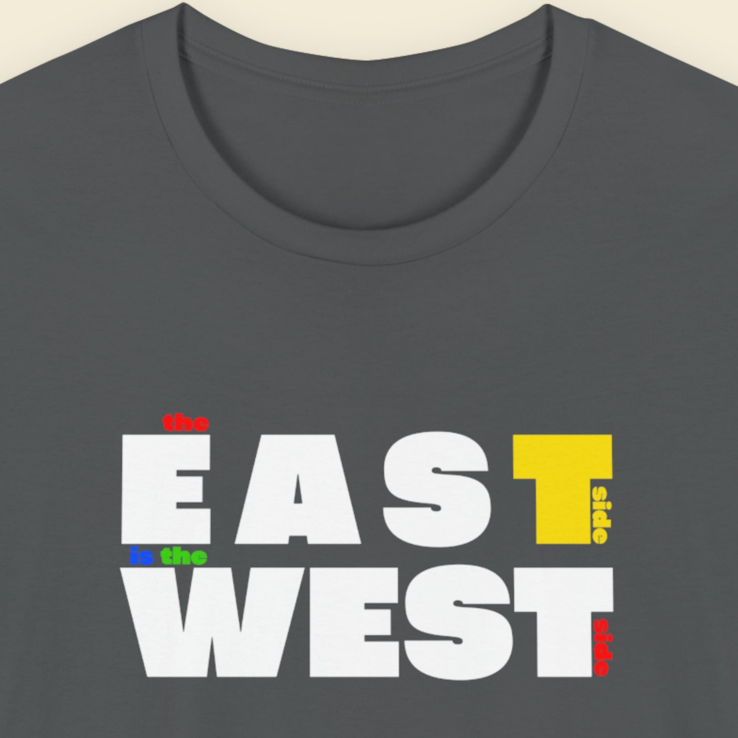 Grey t-shirt with multicolored 'the east side is the west side' text on a beige background.