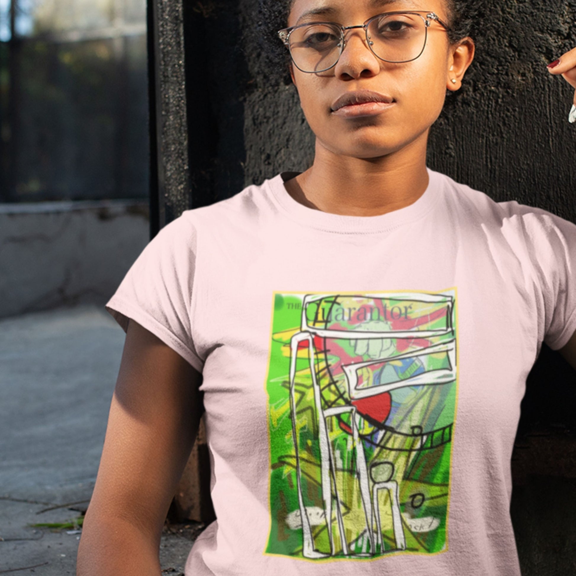 Person wearing a light purple t-shirt with a colorful graphic design on a dark background.