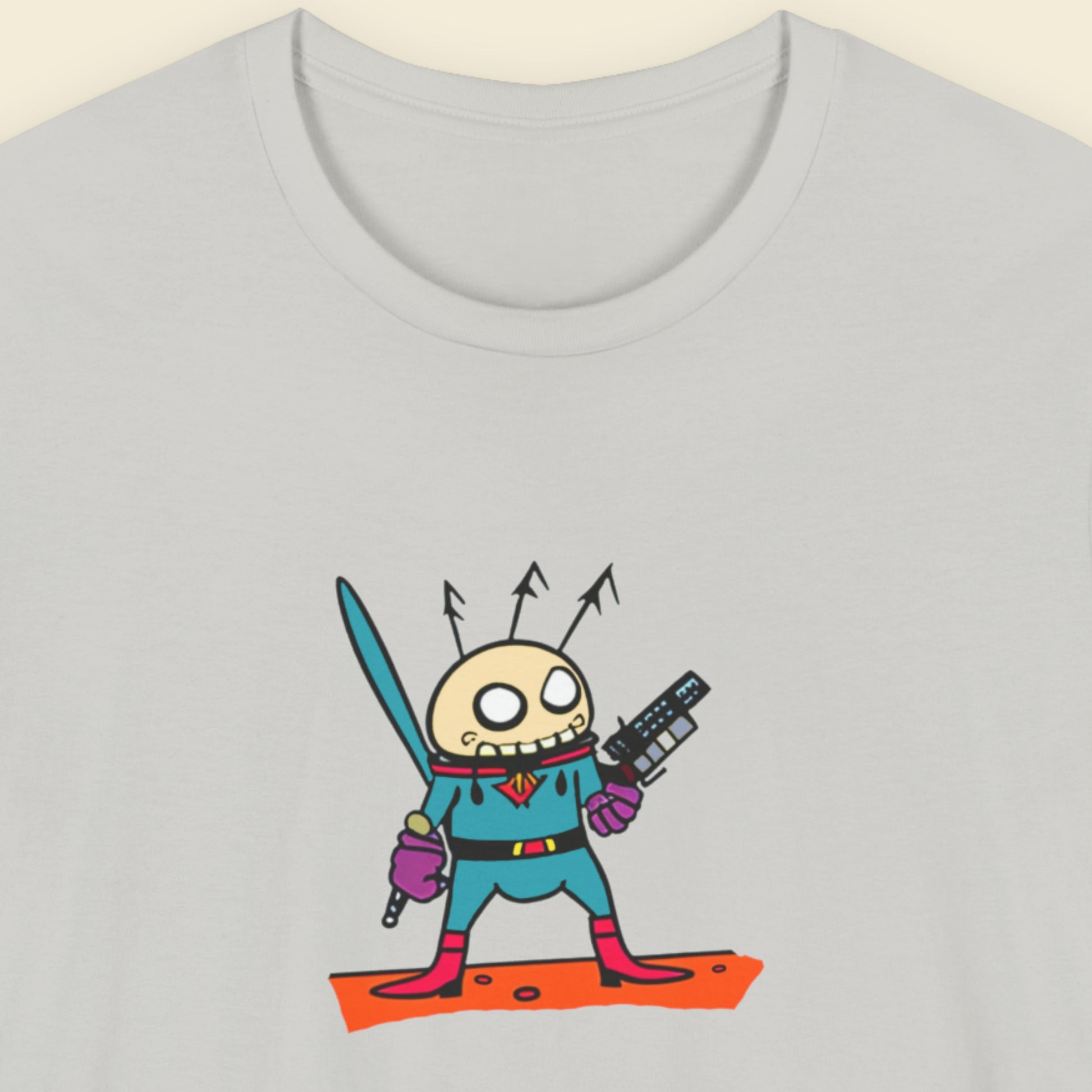 Light grey t-shirt with a fun, colorful cartoon alien illustration on a beige background.