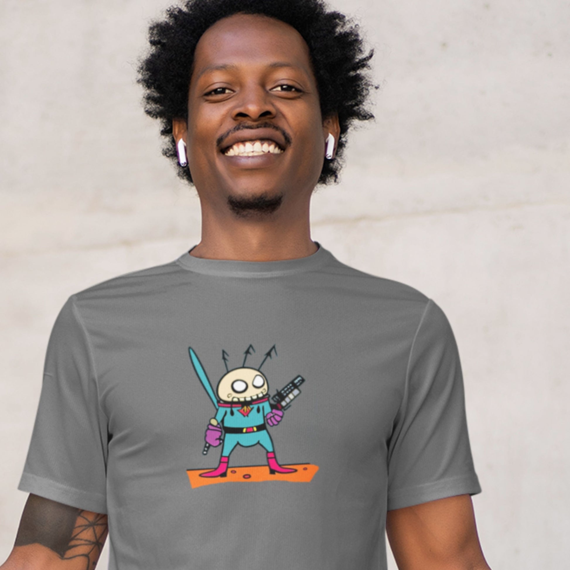 Happy man wearing a dark grey t-shirt with a fun, colorful cartoon alien illustration on a beige background.