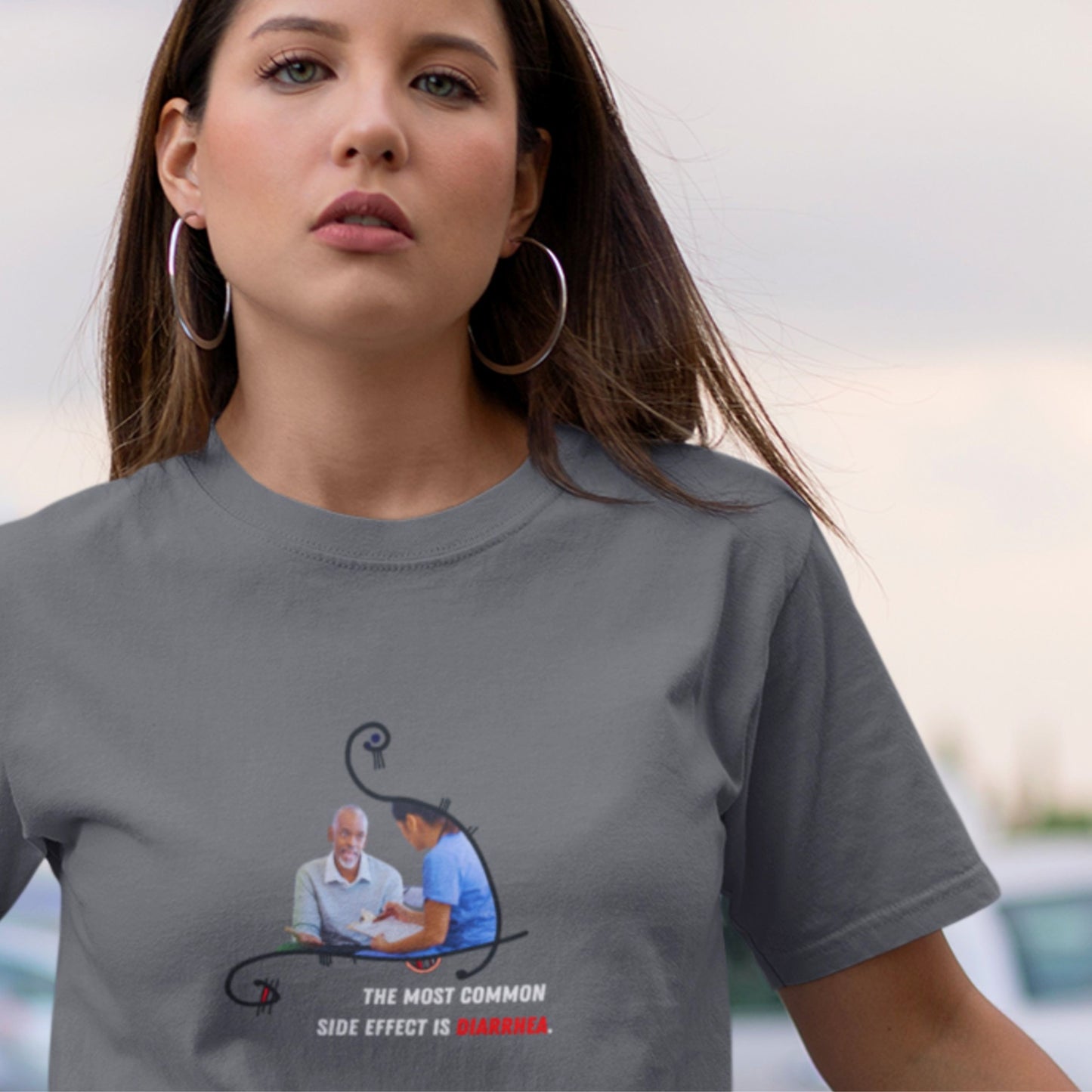 Woman wearing a gray t-shirt with a graphic design and text.