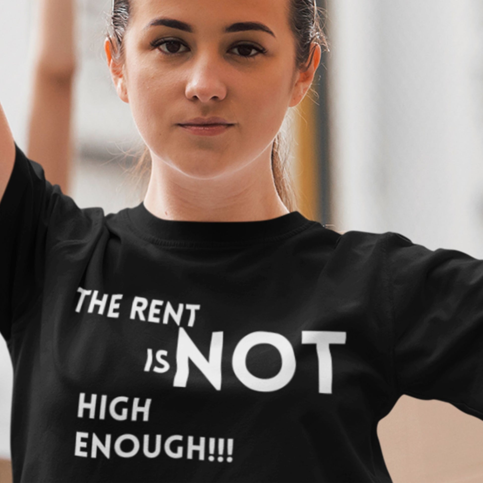 Person wearing a black t-shirt with white text 'THE RENT IS NOT HIGH ENOUGH!!!'