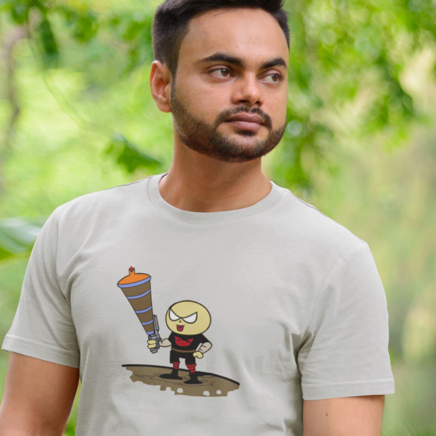 Man wearing a light grey t-shirt with a fun, colorful cartoon illustration outside.