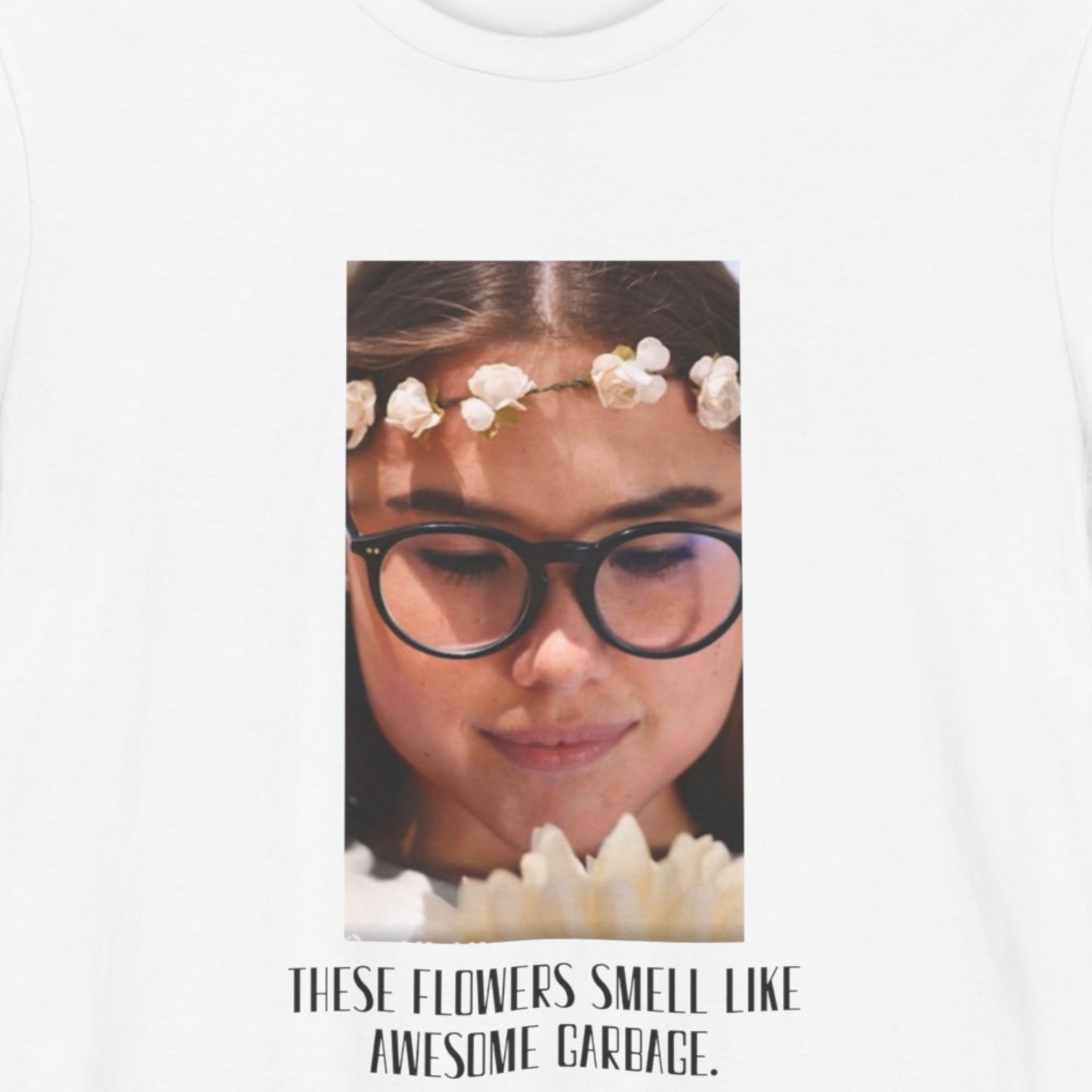 White t-shirt with a graphic of a woman wearing glasses and flowers, text 'These flowers smell like awesome garbage'.