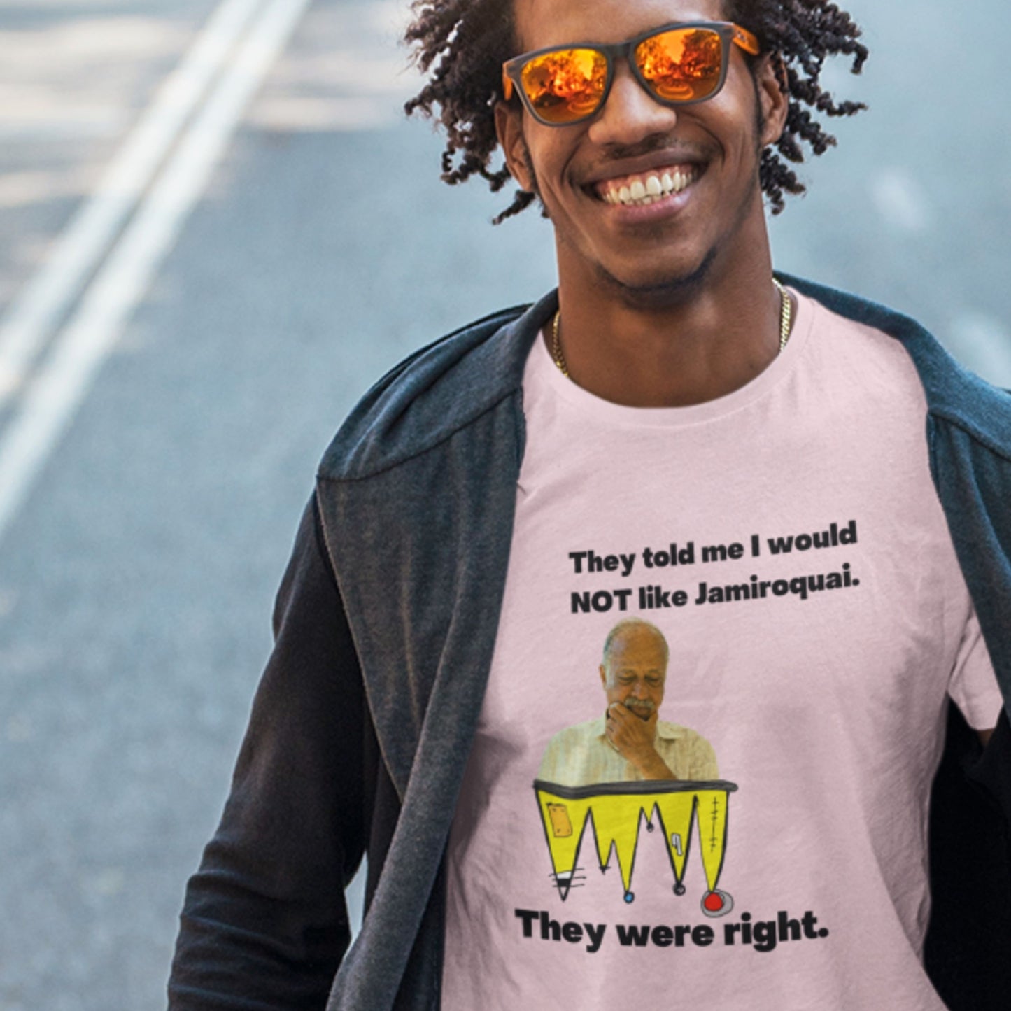 Person wearing a pink t-shirt with a graphic and text, standing on a street.