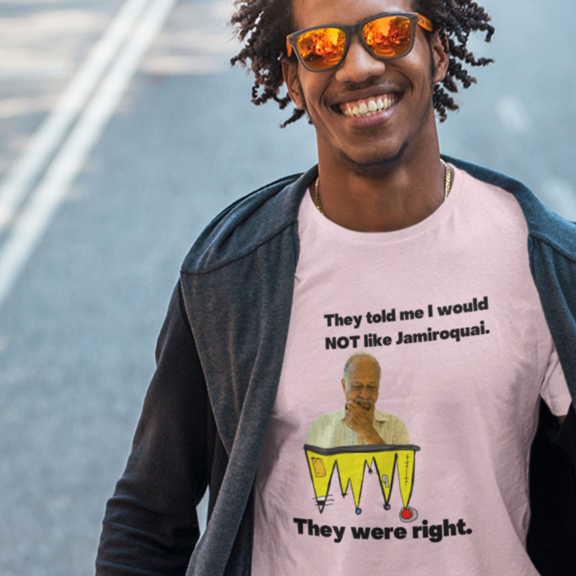 Person wearing a pink t-shirt with a graphic and text, standing on a street.