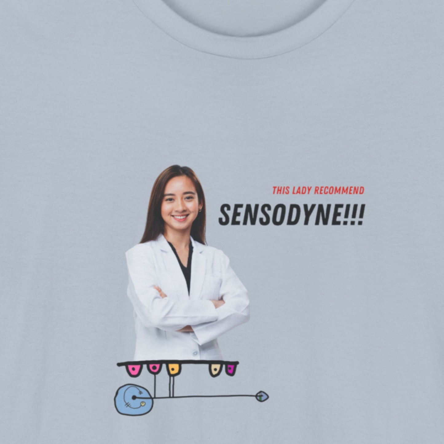 Light blue t-shirt with a colorful abstract drawing, humorous text and an image of a dentist on a beige background.