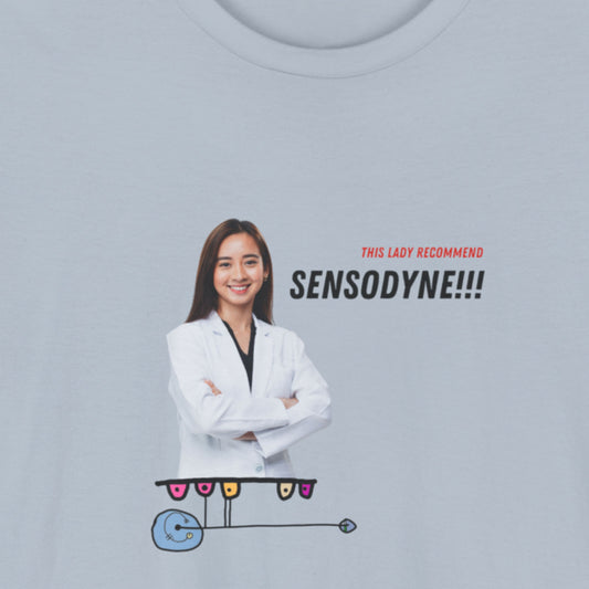 Light blue t-shirt with a colorful abstract drawing, humorous text and an image of a dentist on a beige background.