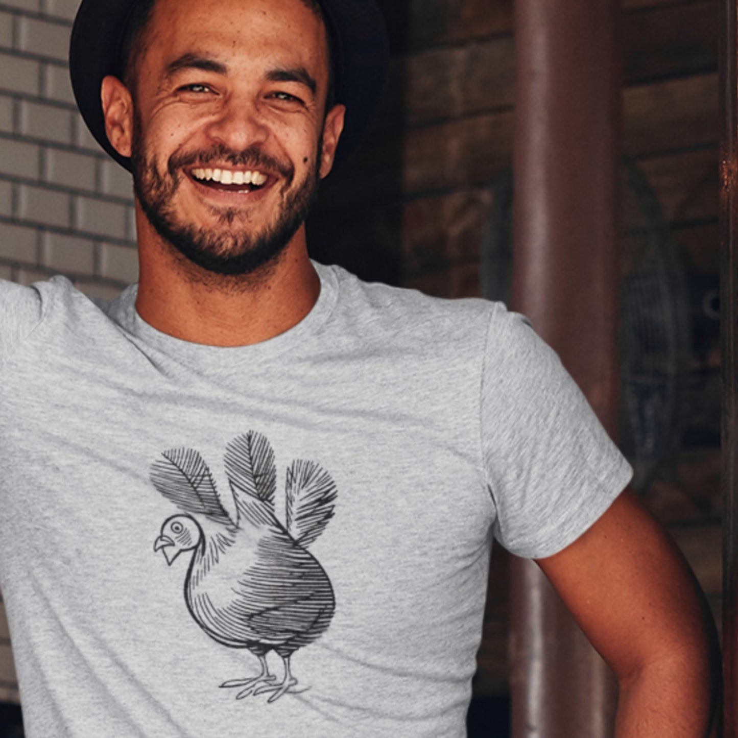 Man wearing a light gray t-shirt with a chicken design, smiling outdoors.