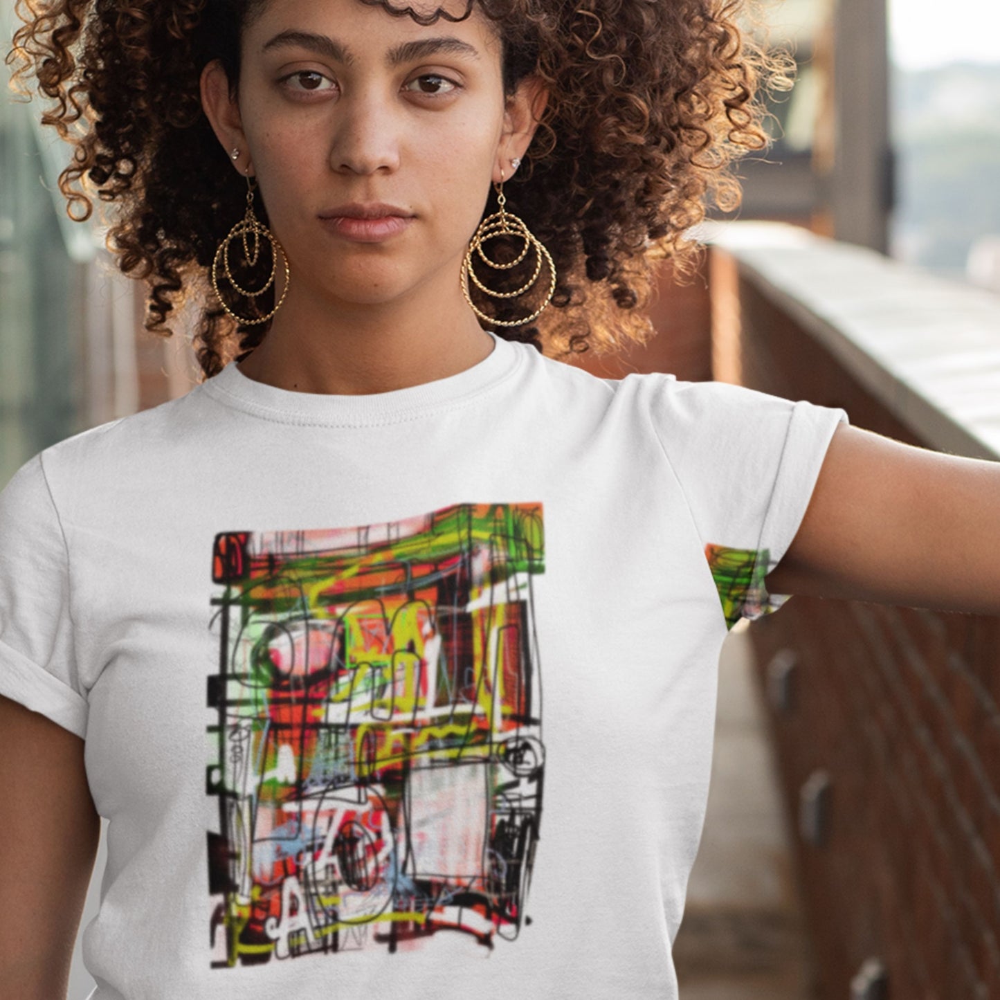 Woman wearing a white t-shirt with colorful abstract design outdoors.