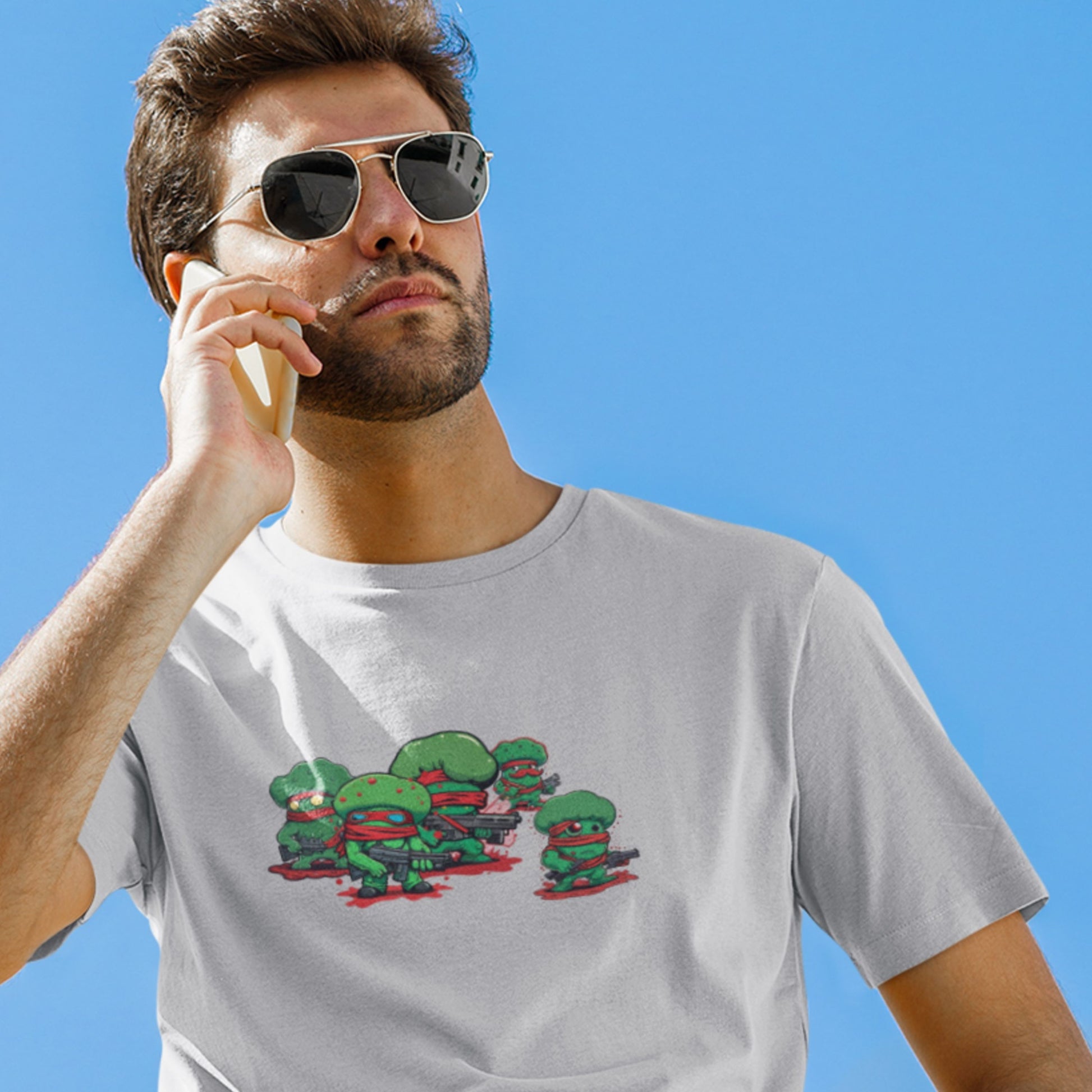 Man wearing a gray t-shirt with a graphic design against a clear blue sky