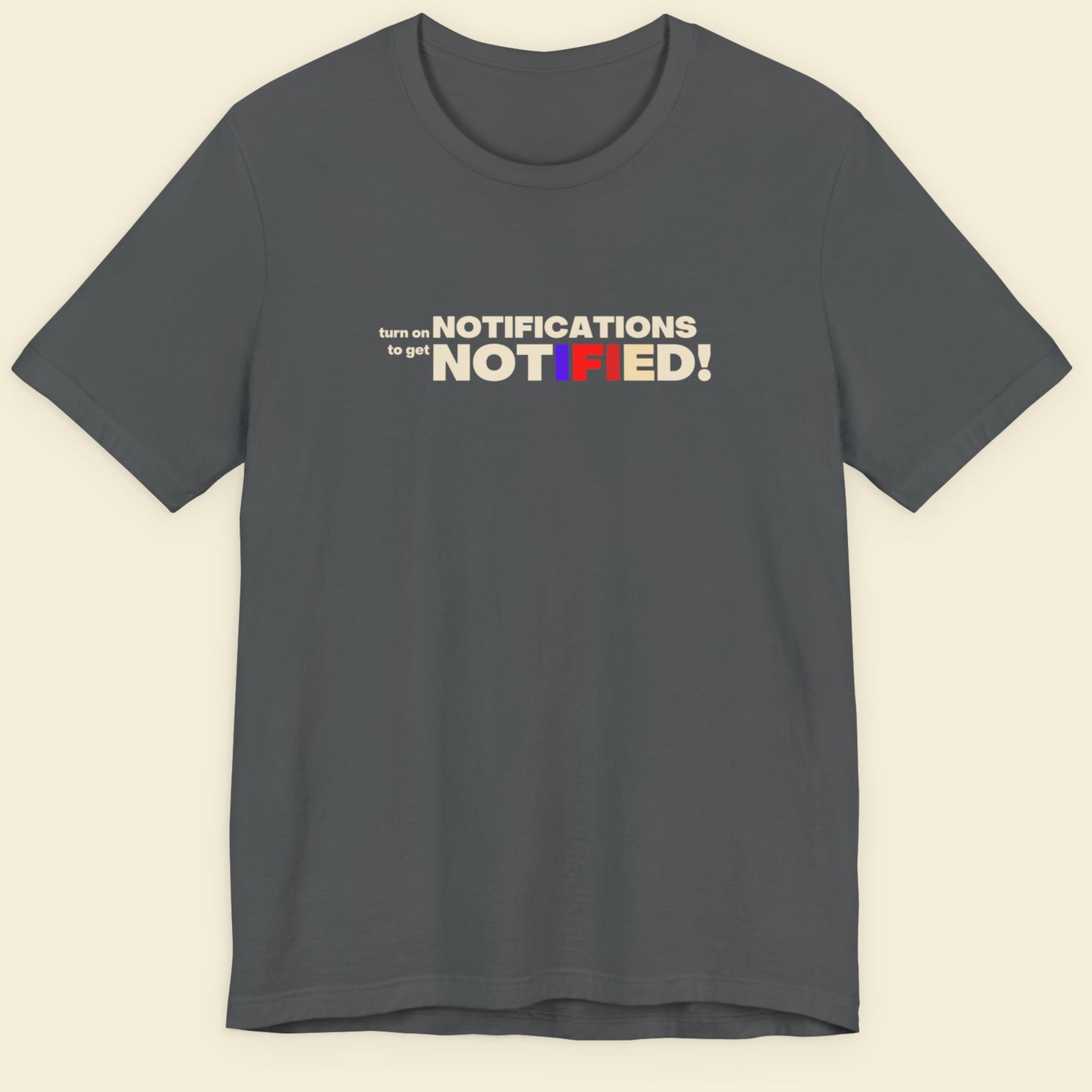 Gray t-shirt with colorful text design on a beige background.