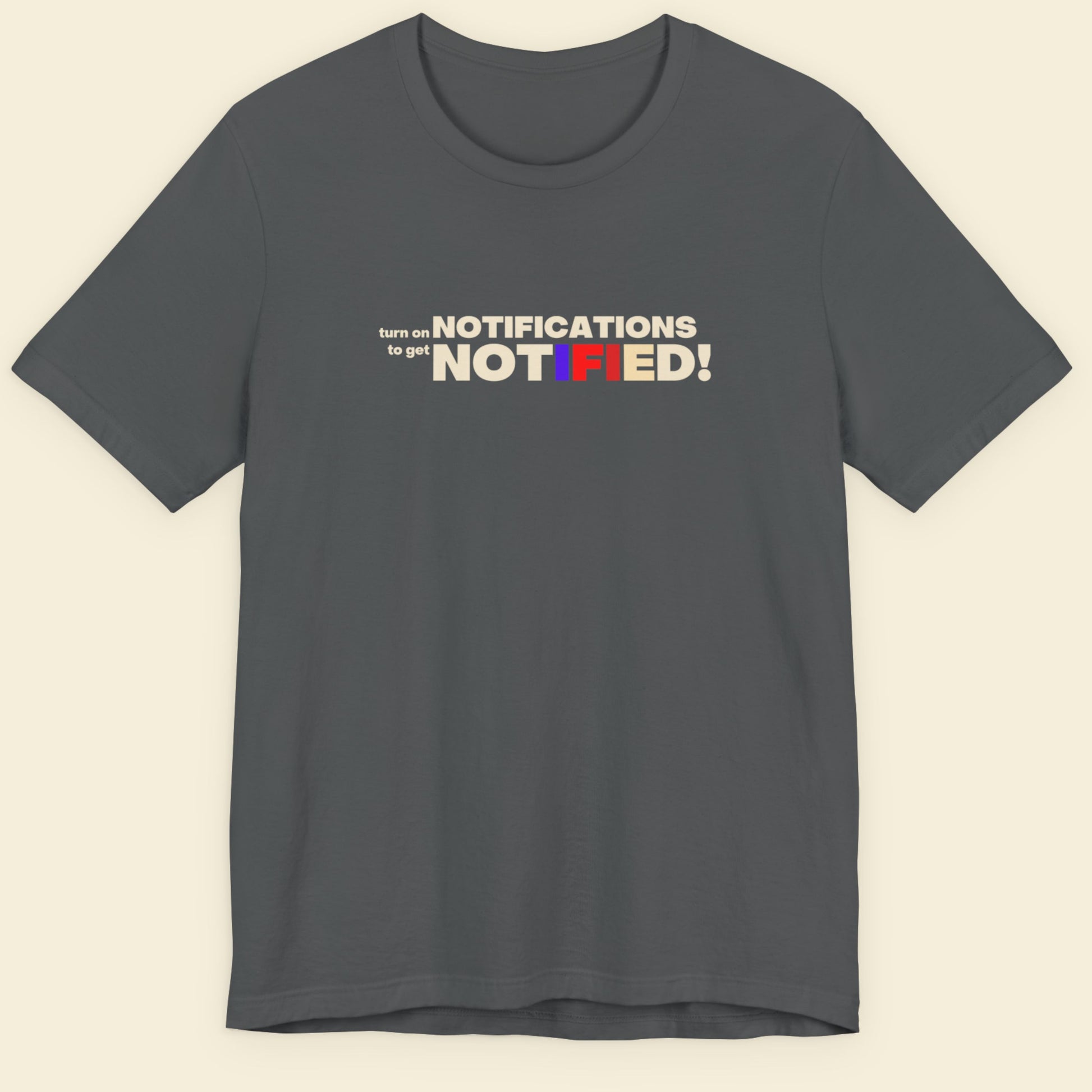 Gray t-shirt with colorful text design on a beige background.