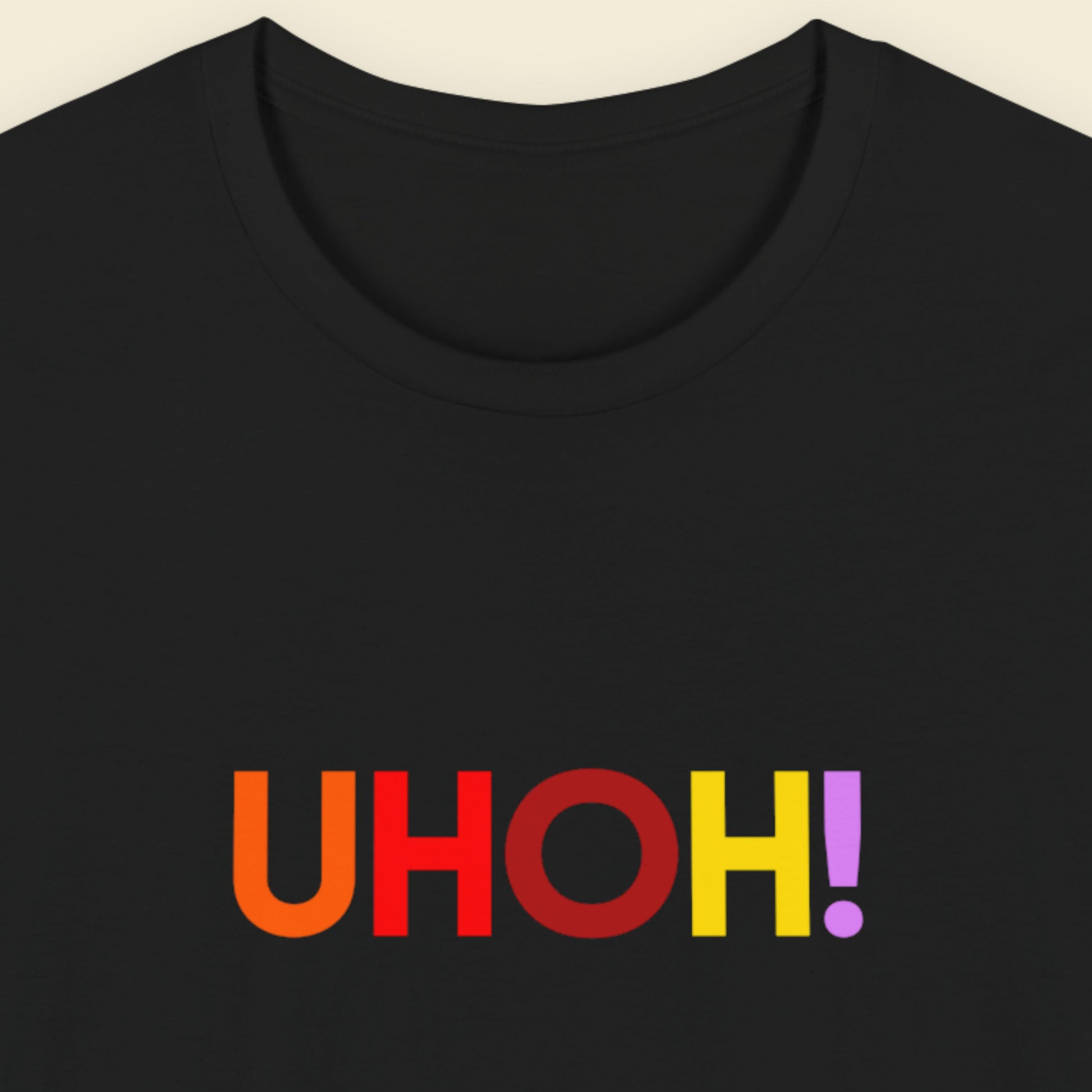 Black t-shirt with colorful 'UHOH!' text on a beige background.
