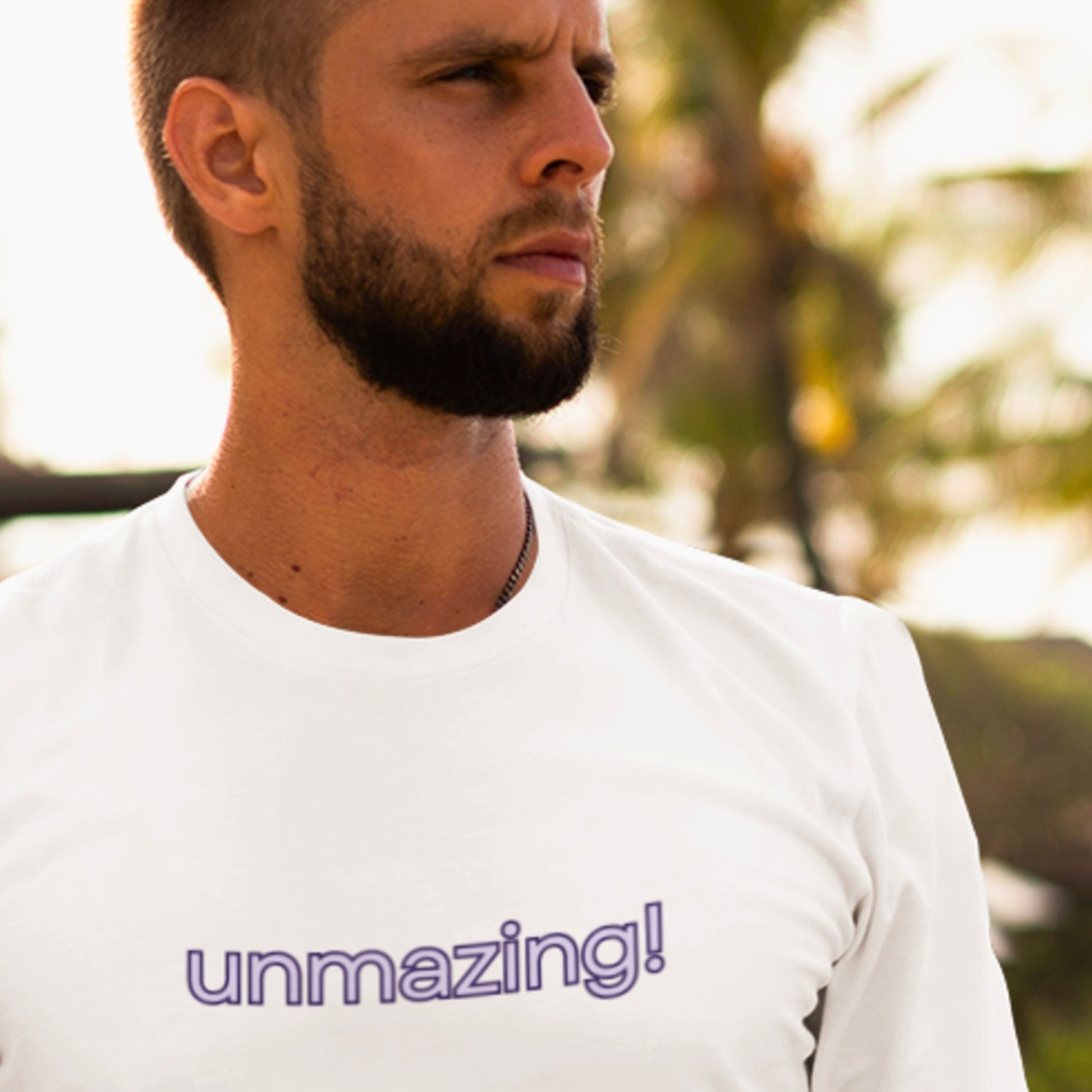 Man wearing a white t-shirt with 'unmazing!' text outdoors.