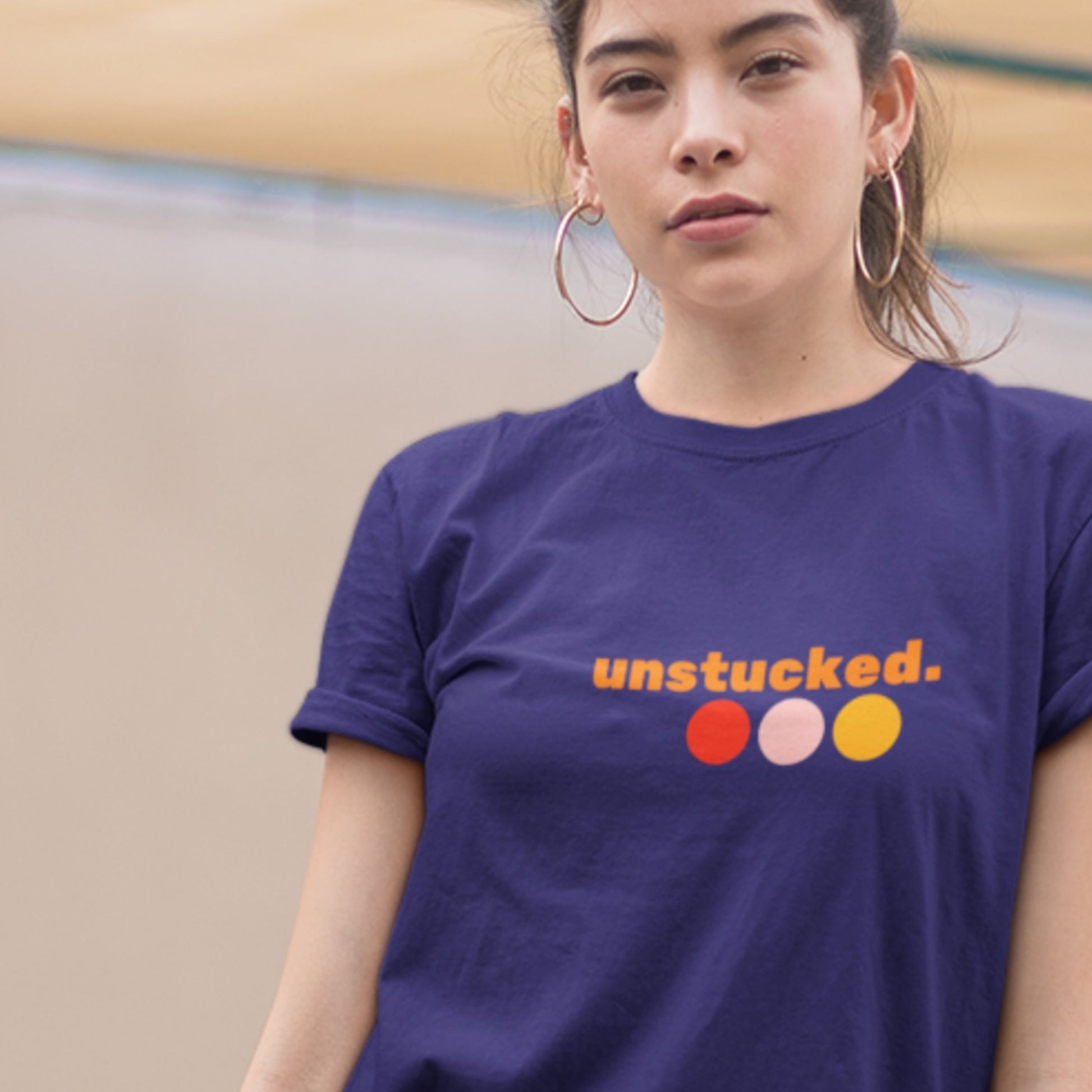 Person wearing a navy blue t-shirt with 'unstucked.' text and colorful dots.