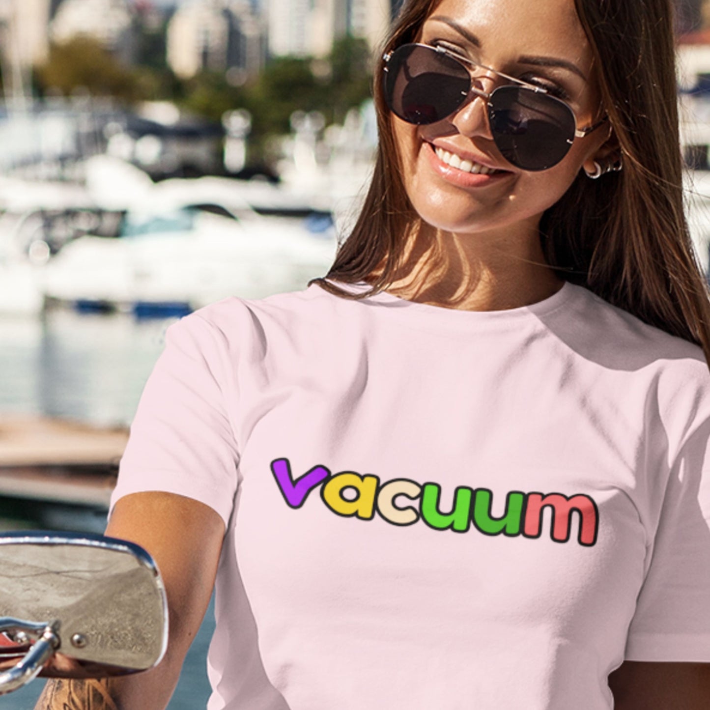 Woman wearing a colorful 'Vacuum' t-shirt by a marina.