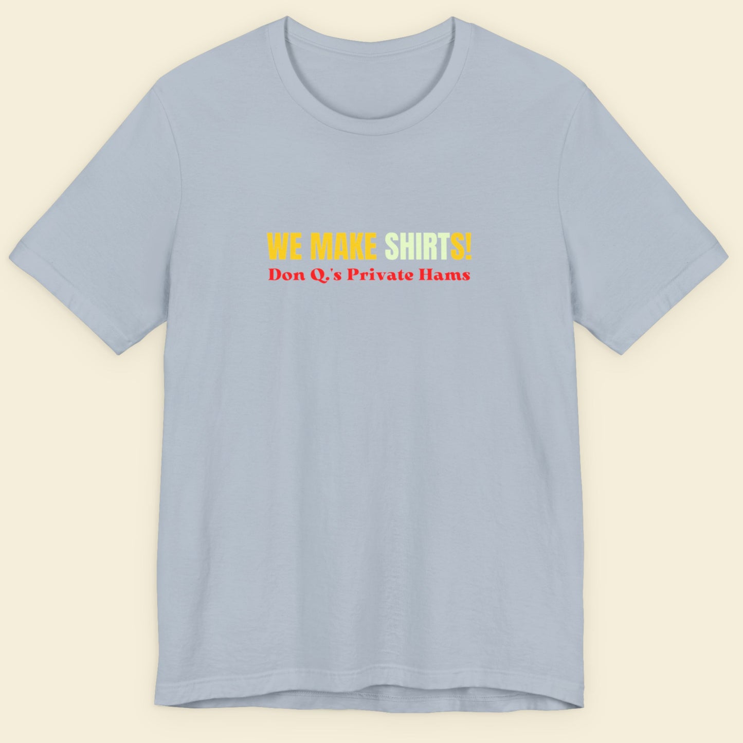 Light blue t-shirt with multicolored 'we make shirts!' text on a beige background.